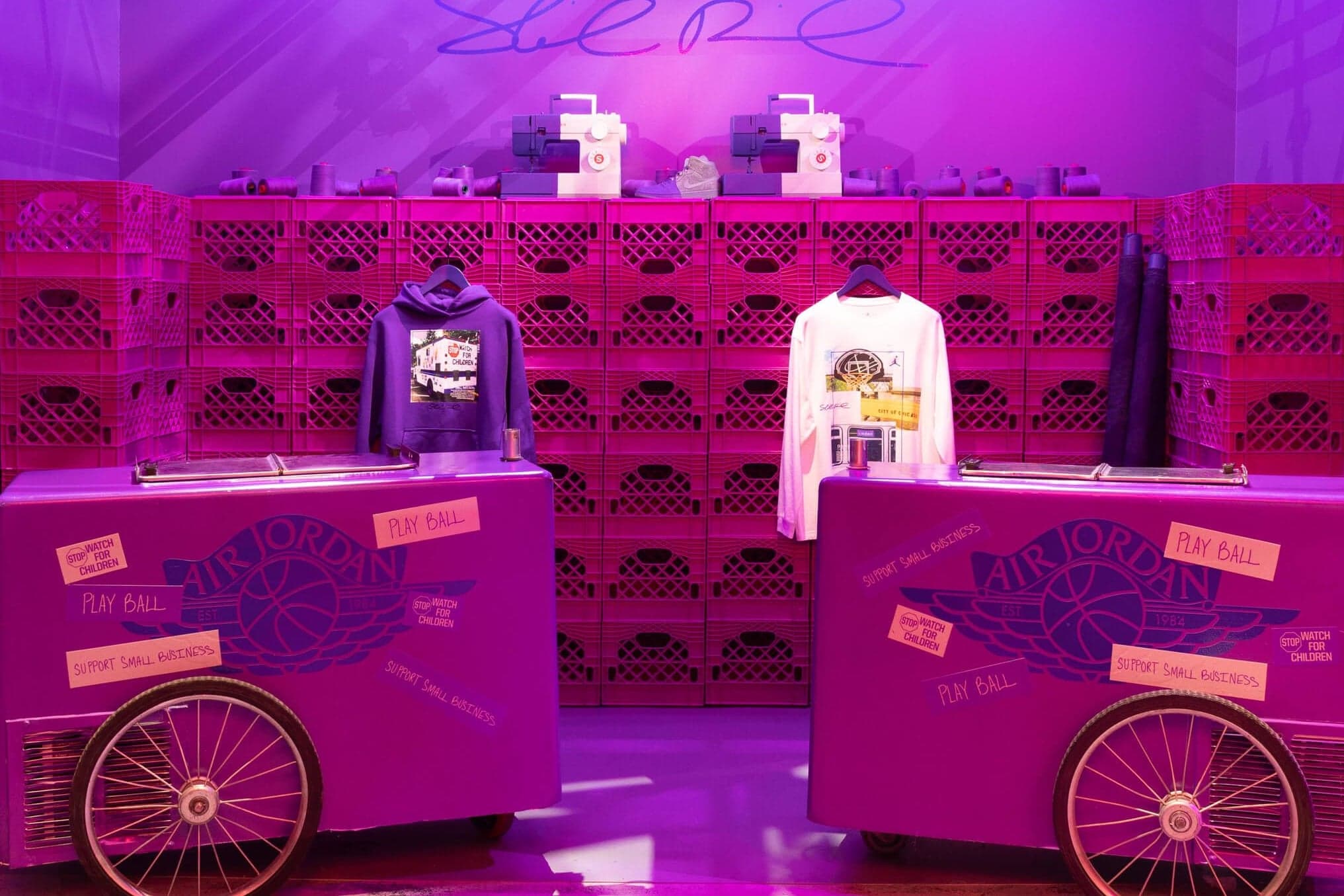 Purple merch carts with Air Jordan wings in front of a wall of pink crates