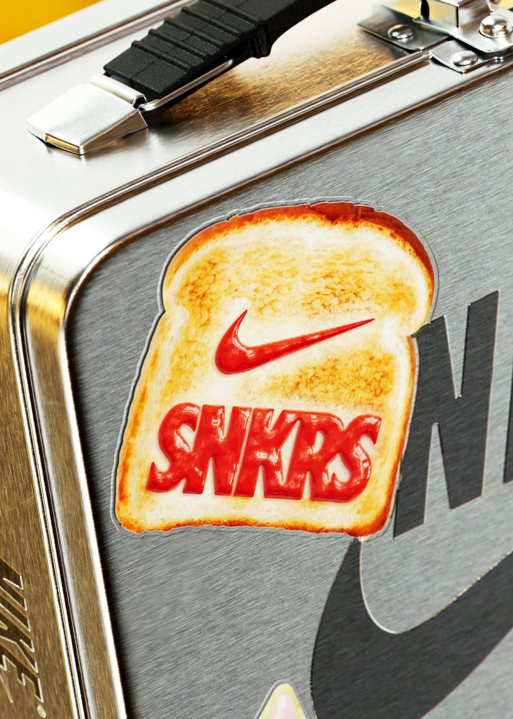 A metal lunchbox with a SNKRS toast graphic