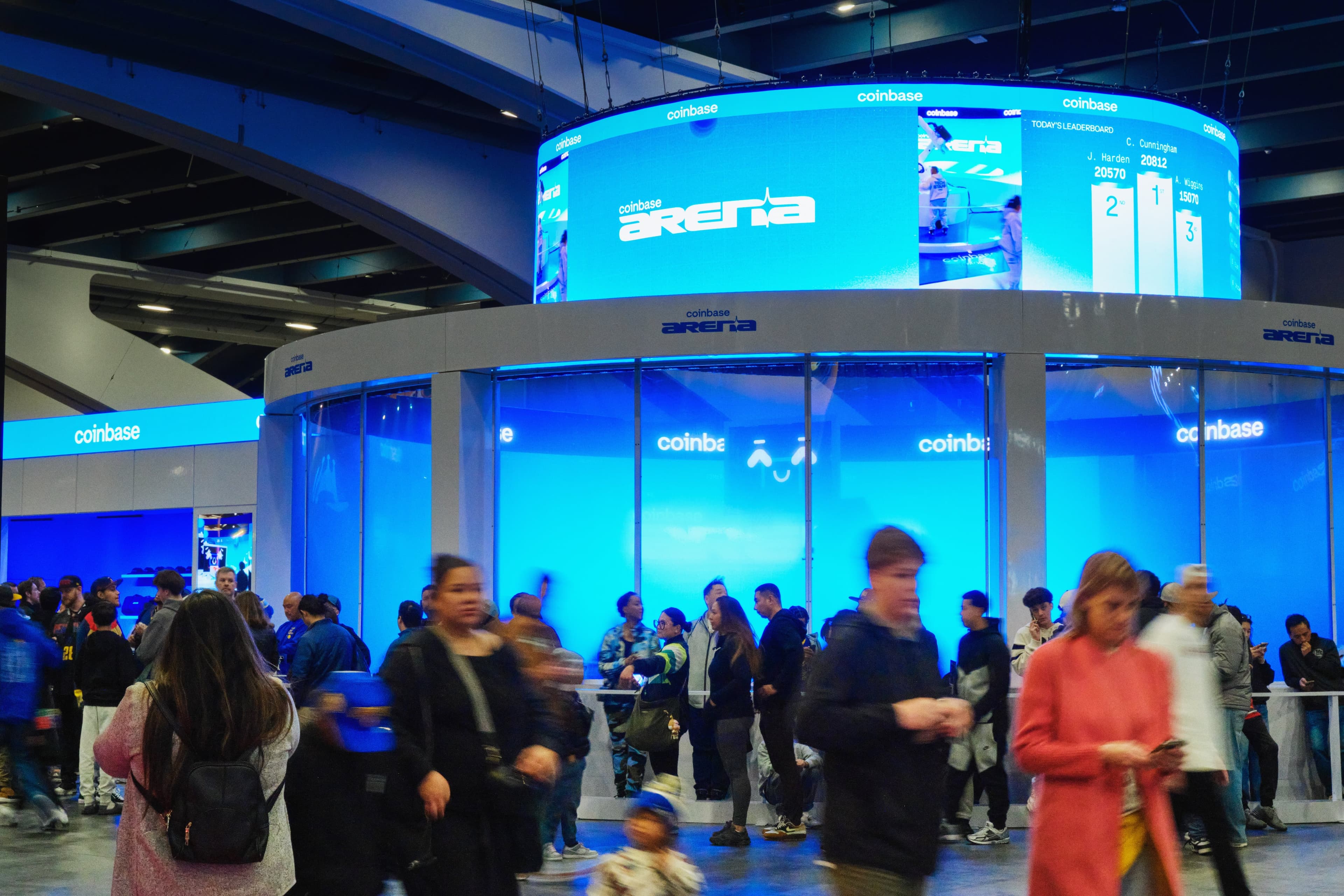 Crowds walking past Coinbase Arena beneath its circular LED screen