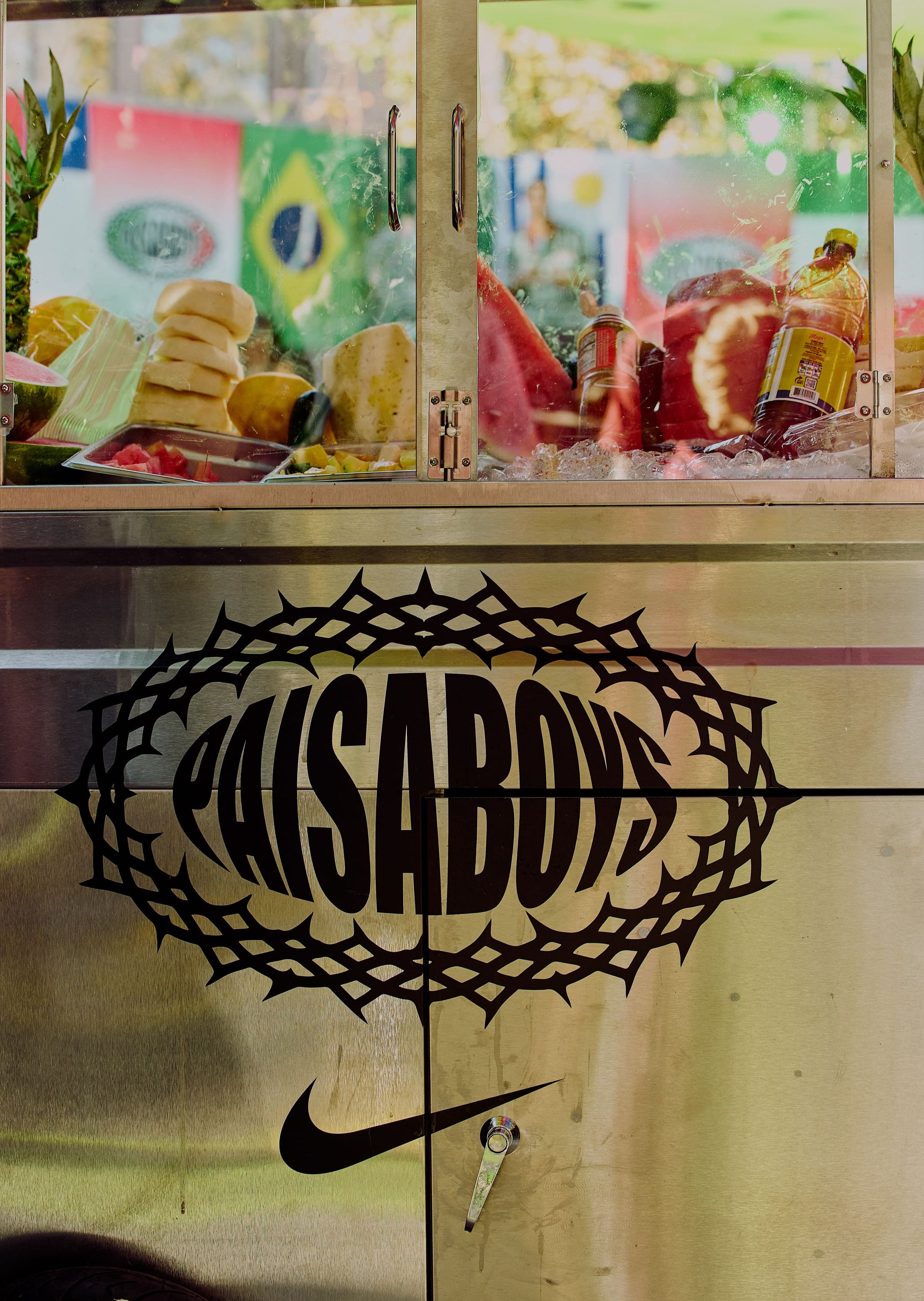 The Paisa Boys logo and a Nike swoosh on a glass case of Mexican snacks