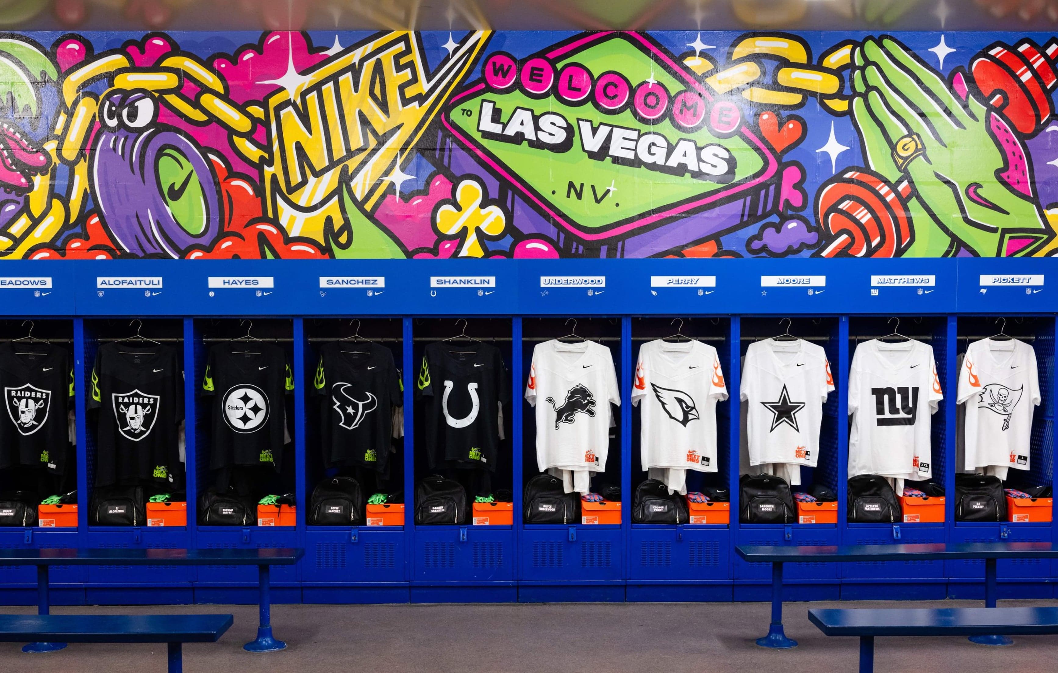 The locker room’s lockers with team jerseys beneath a mural of the “Welcome to Las Vegas” sign