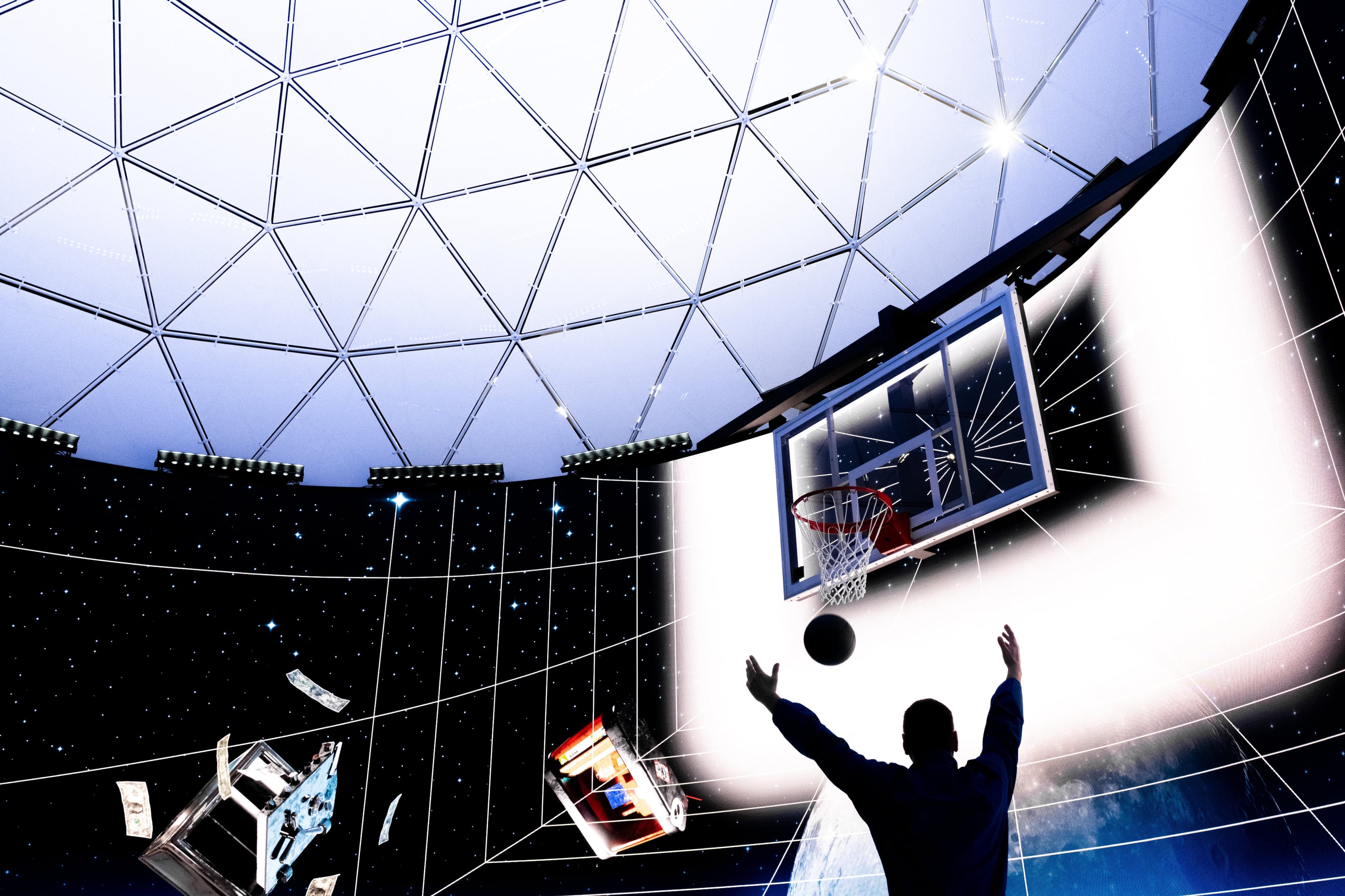 A player silhouetted against the glowing LED wall shoots for the hoop under the dome