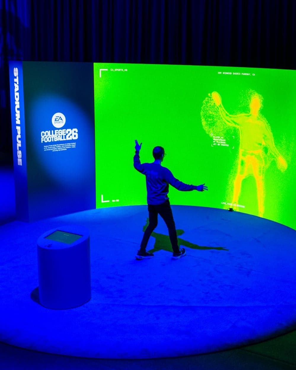 A guest striking a pose at the Stadium Pulse screen, which shows their figure in glowing particles on green