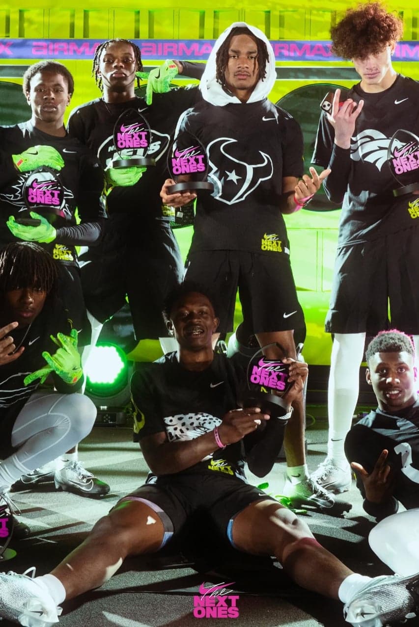 Players posing at night in black “The Next Ones” shirts under green light