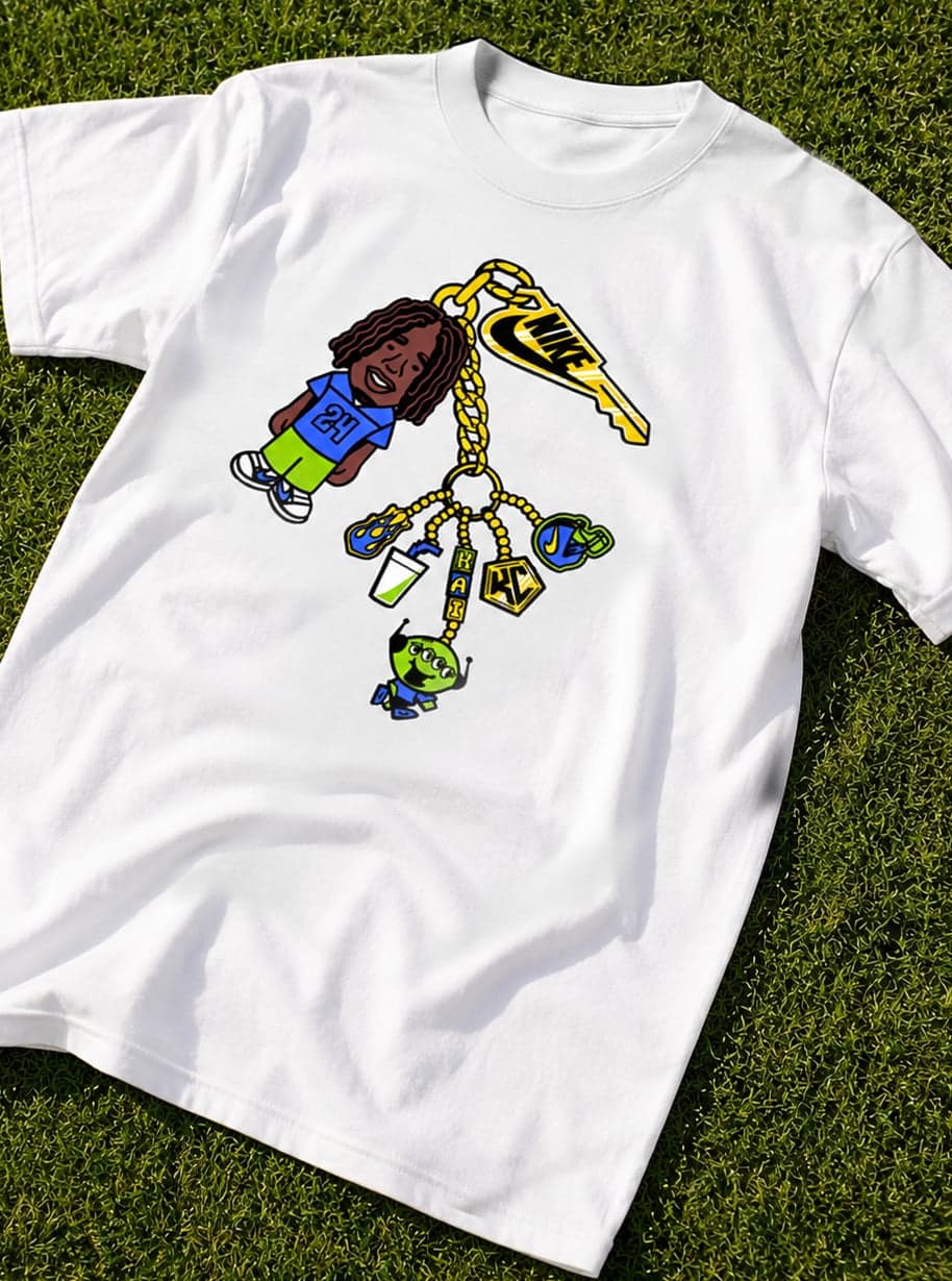A white T-shirt printed with the keychain character illustration lying on grass
