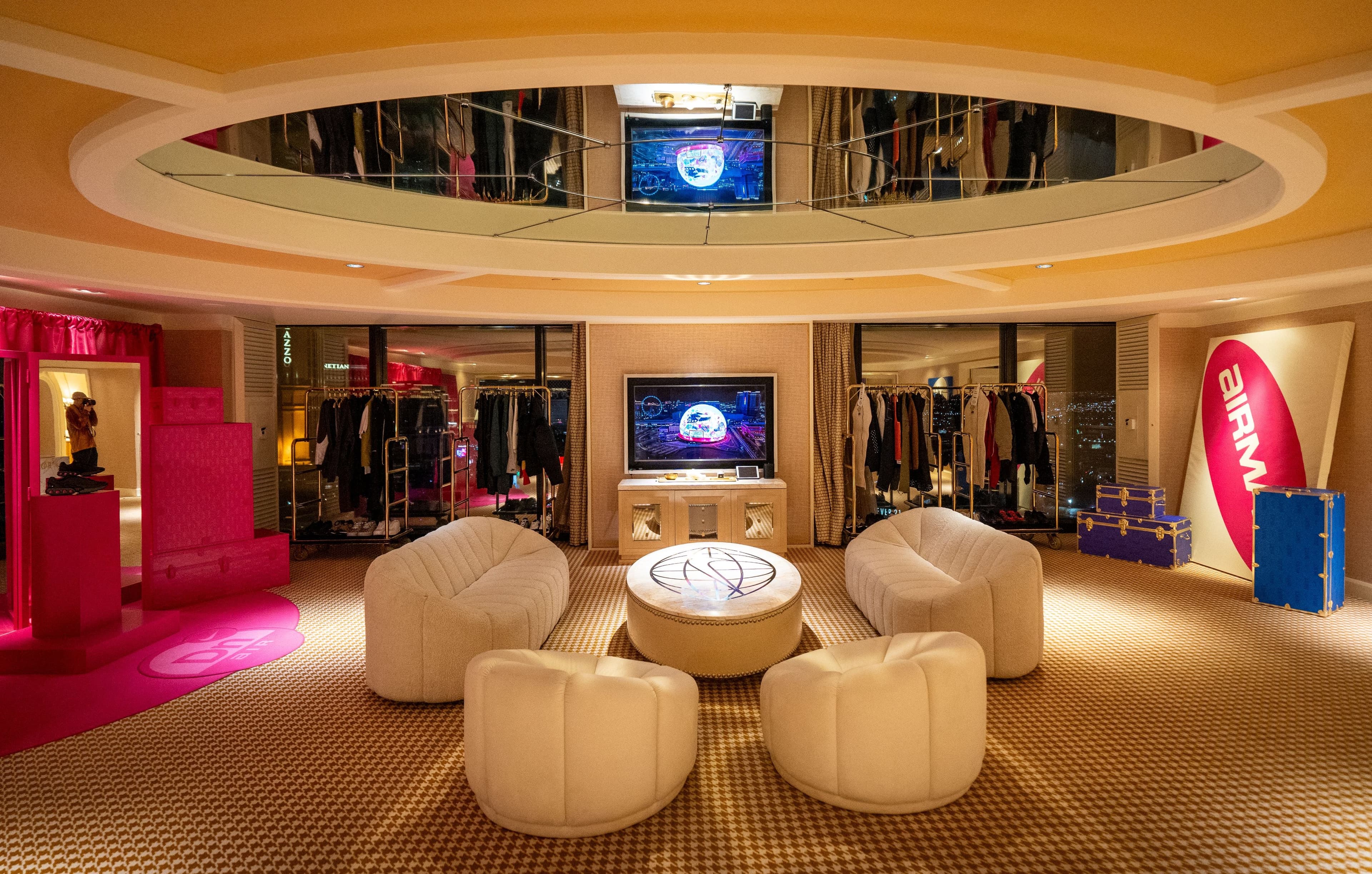 The penthouse lounge: white armchairs around a round table under a mirrored ceiling, with clothing rails and screens behind