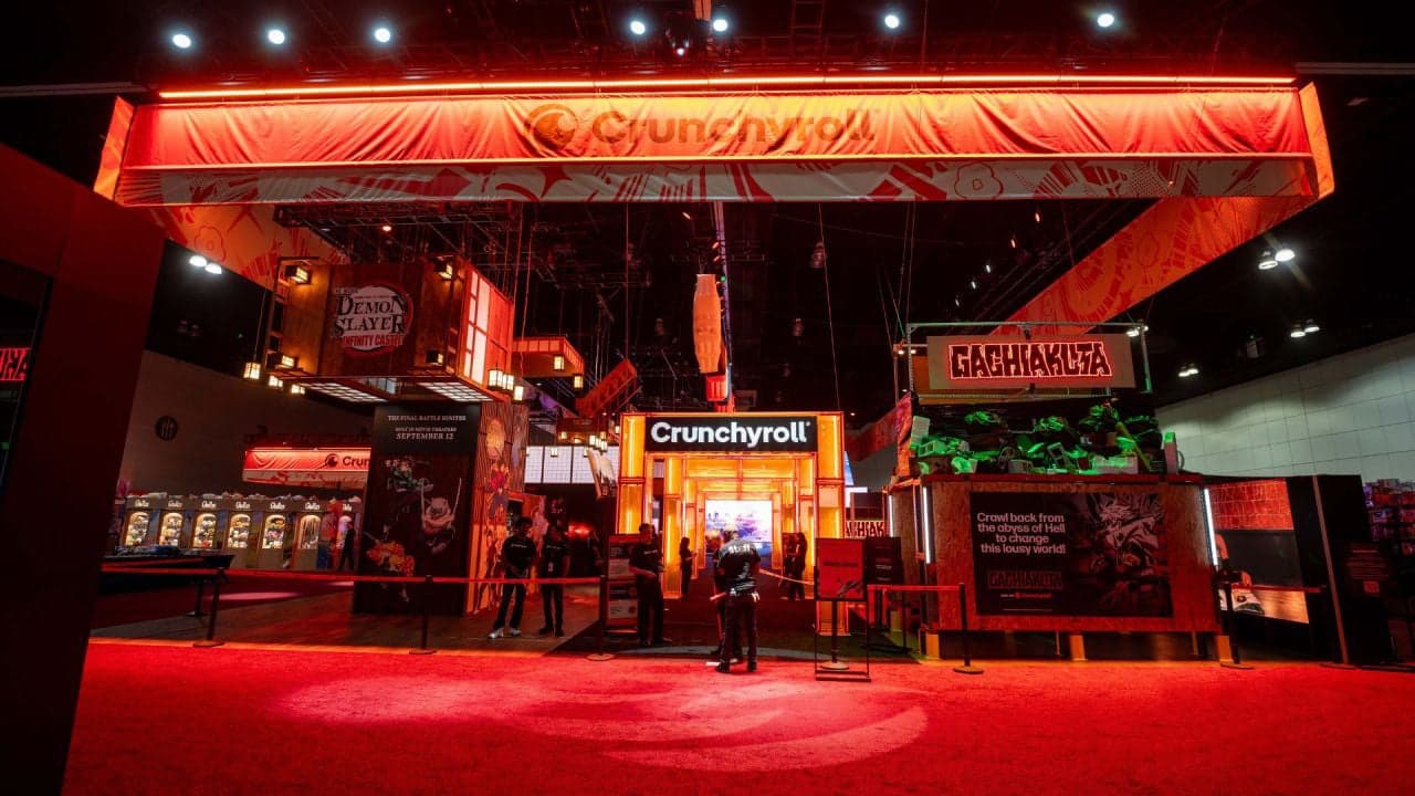 The Crunchyroll booth at Anime Expo under red light, with the Gachiakuta area on the right
