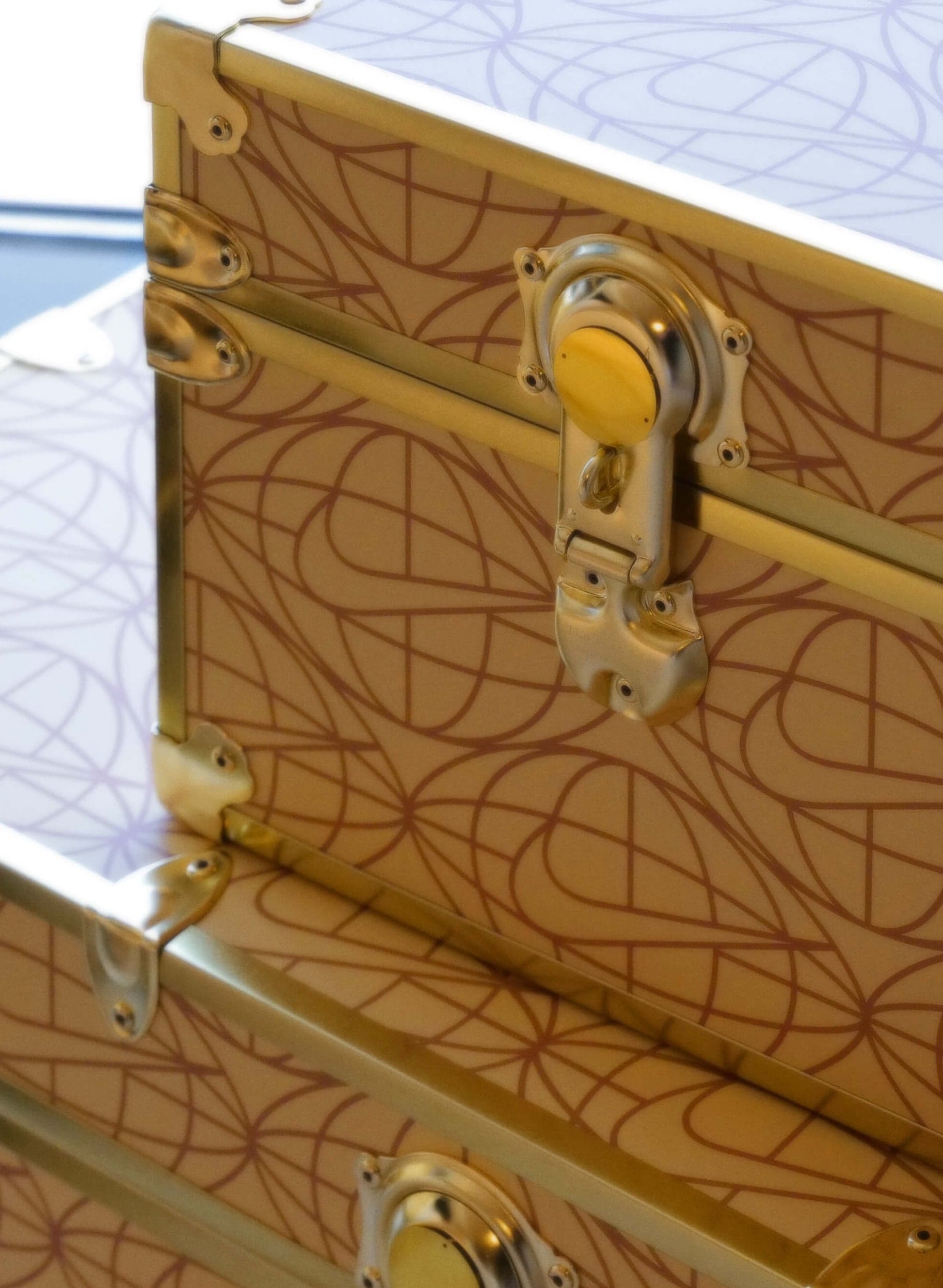 Gold trunks with a globe-and-swoosh pattern and a brass latch