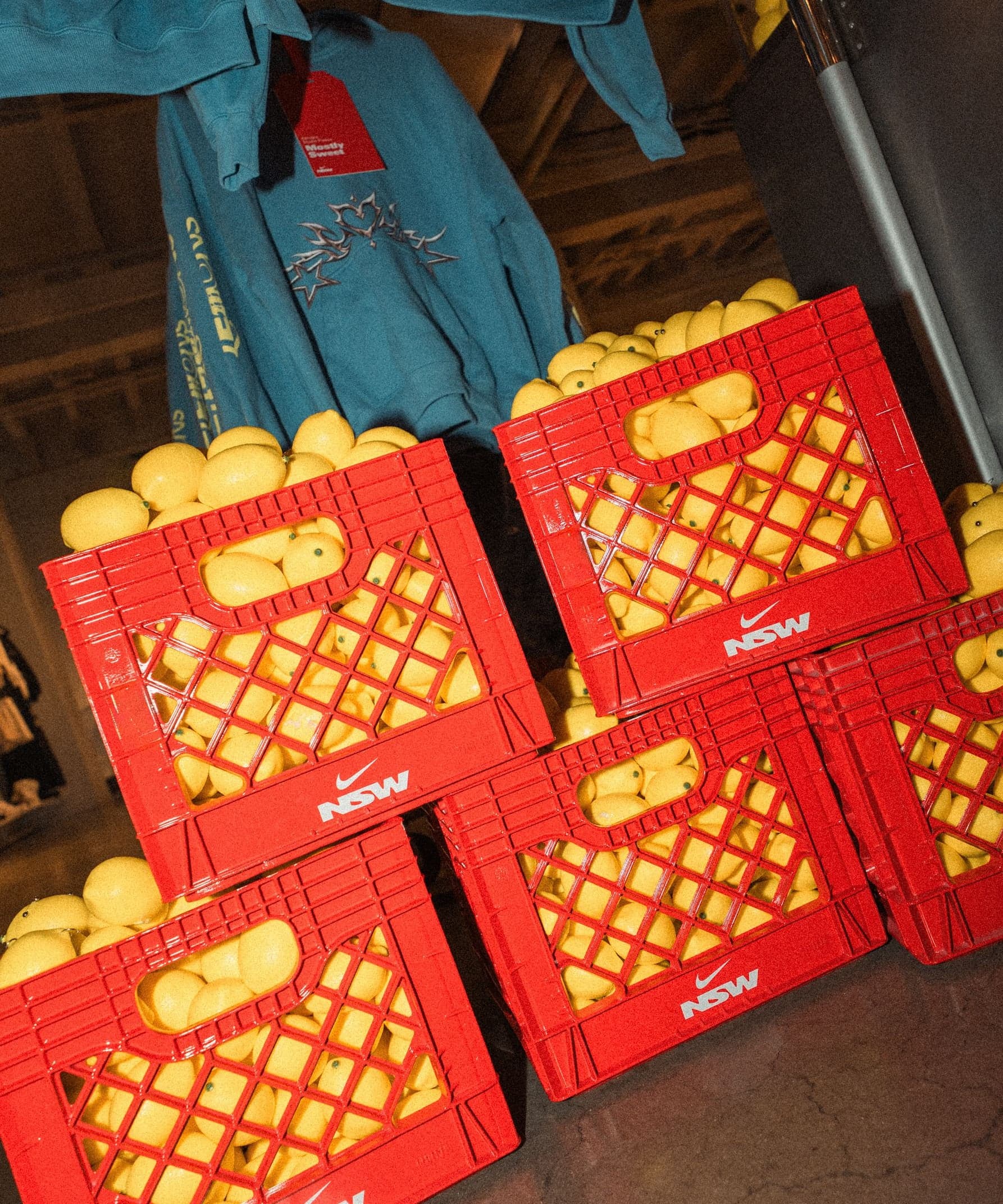 Red milk crates filled with lemons under blue hoodies