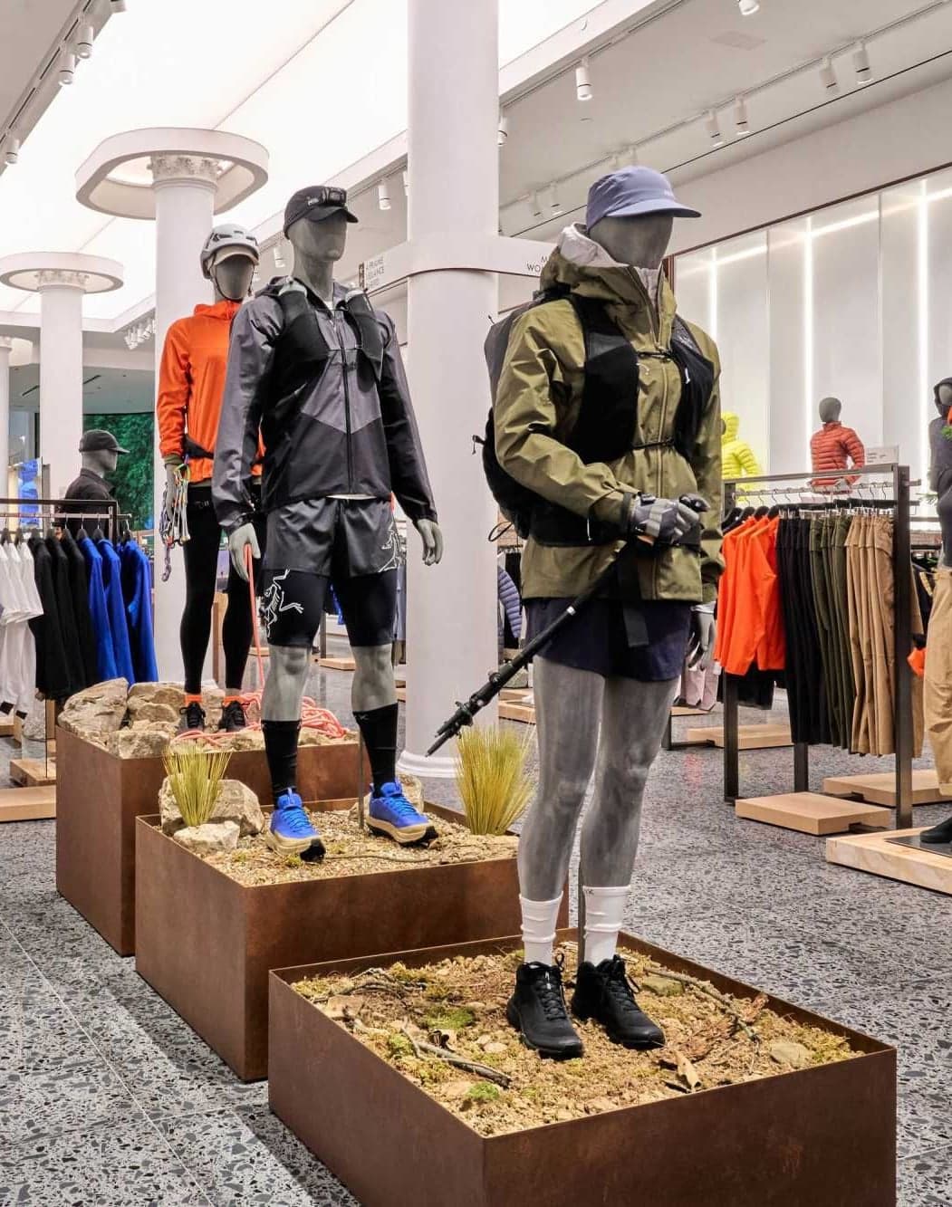 Mannequins in outdoor jackets on wooden plinths across the store floor
