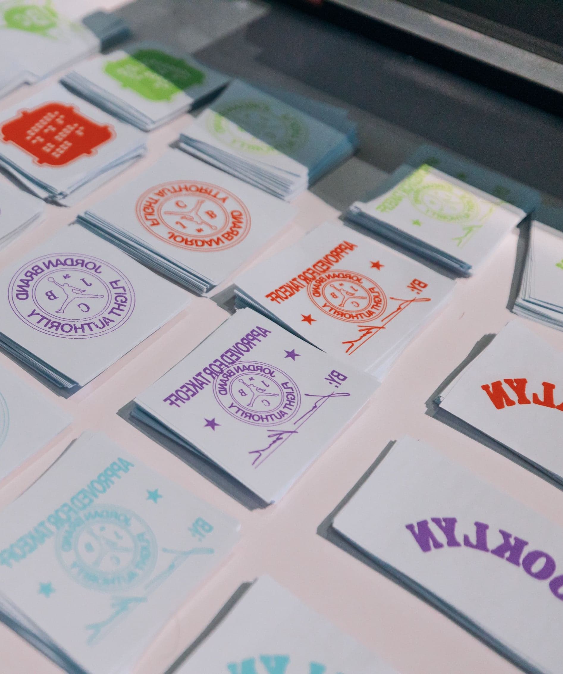 Sheets of pastel Brooklyn stickers fanned across a table