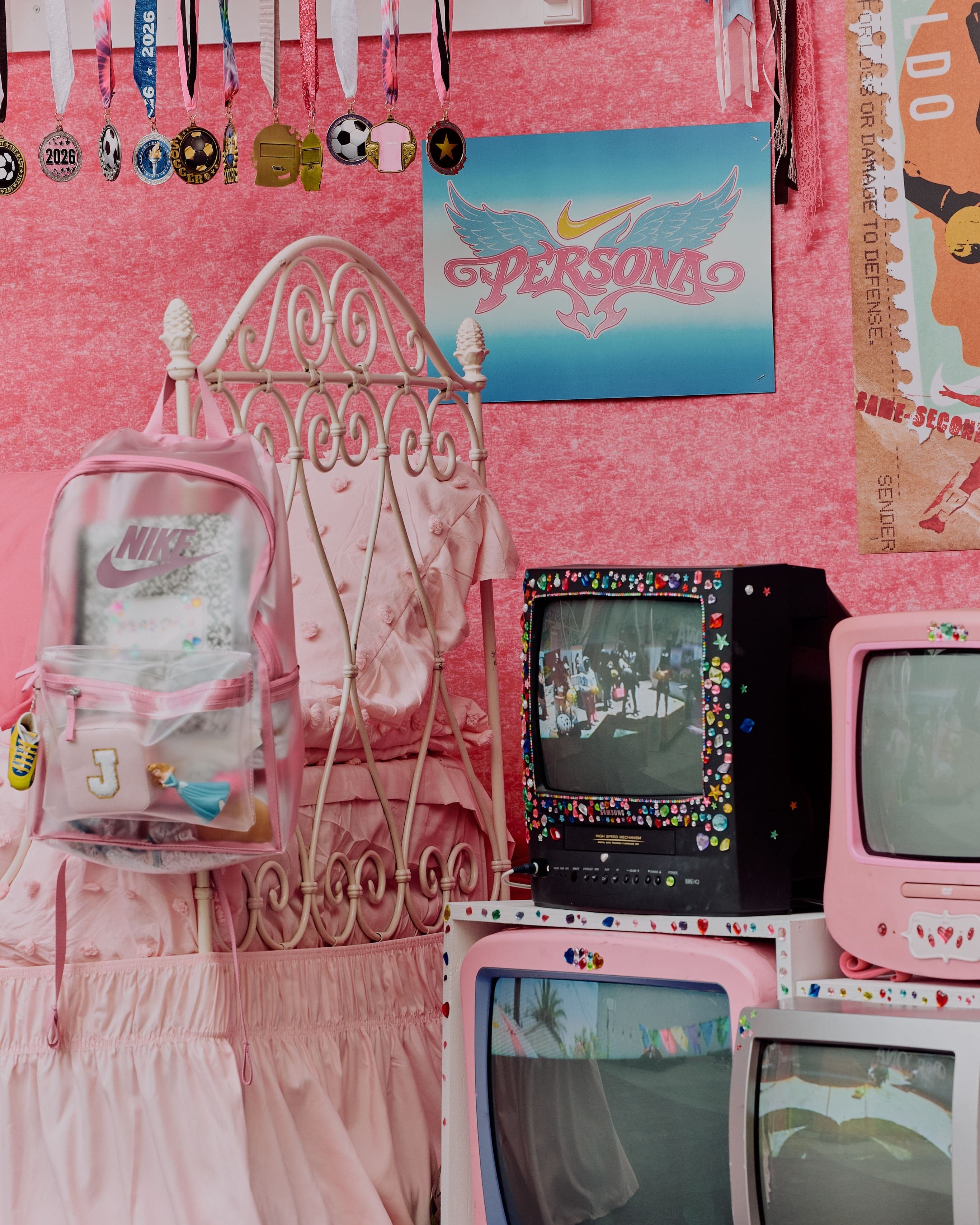 A pink room with a frilly bed canopy and stacked vintage TVs