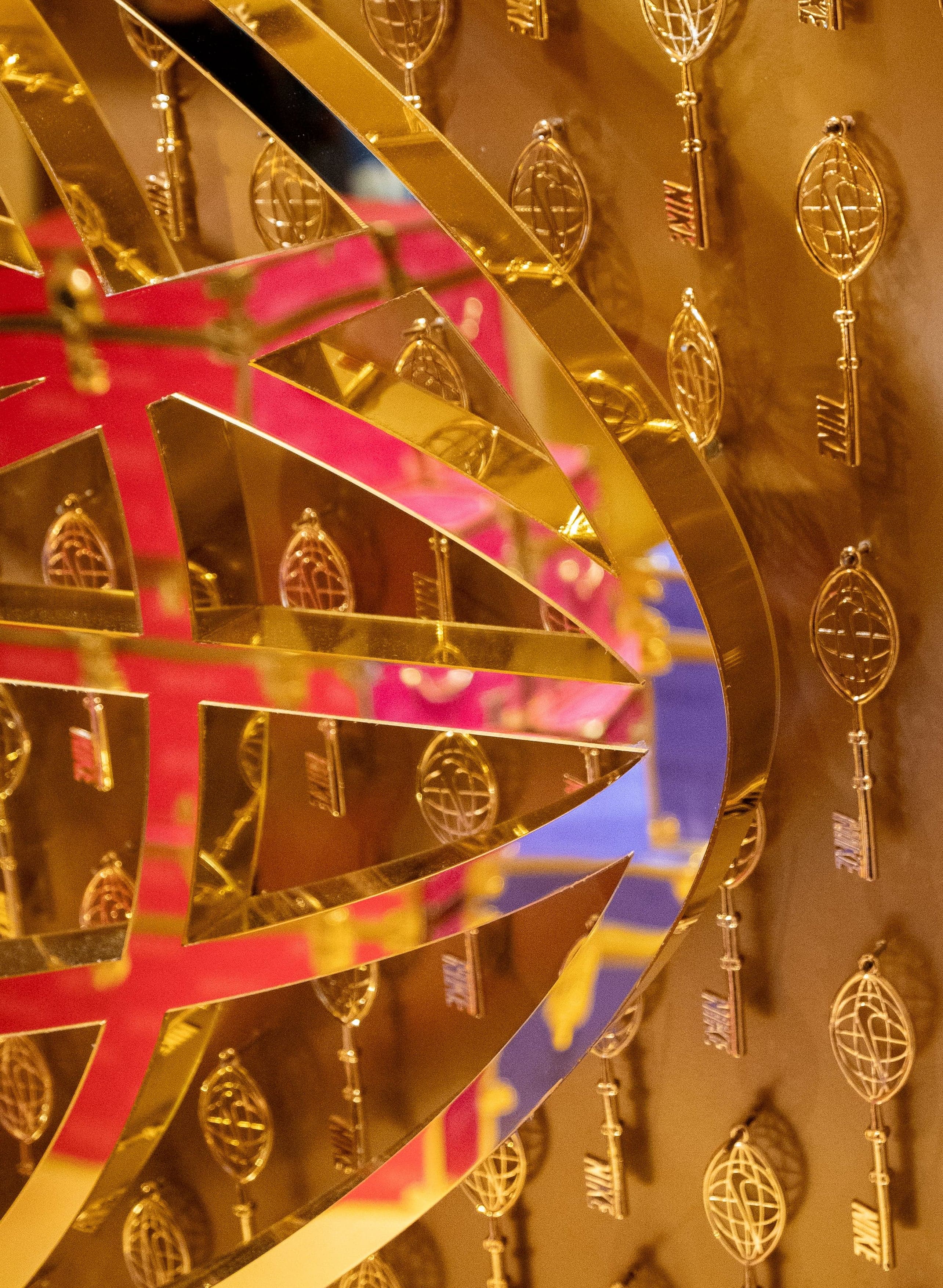 A gold and pink globe sculpture in front of a wall of gold hotel keys