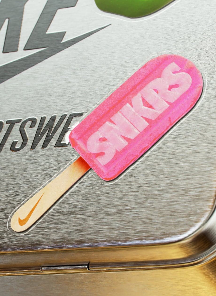 A metal lunchbox with a pink SNKRS popsicle graphic