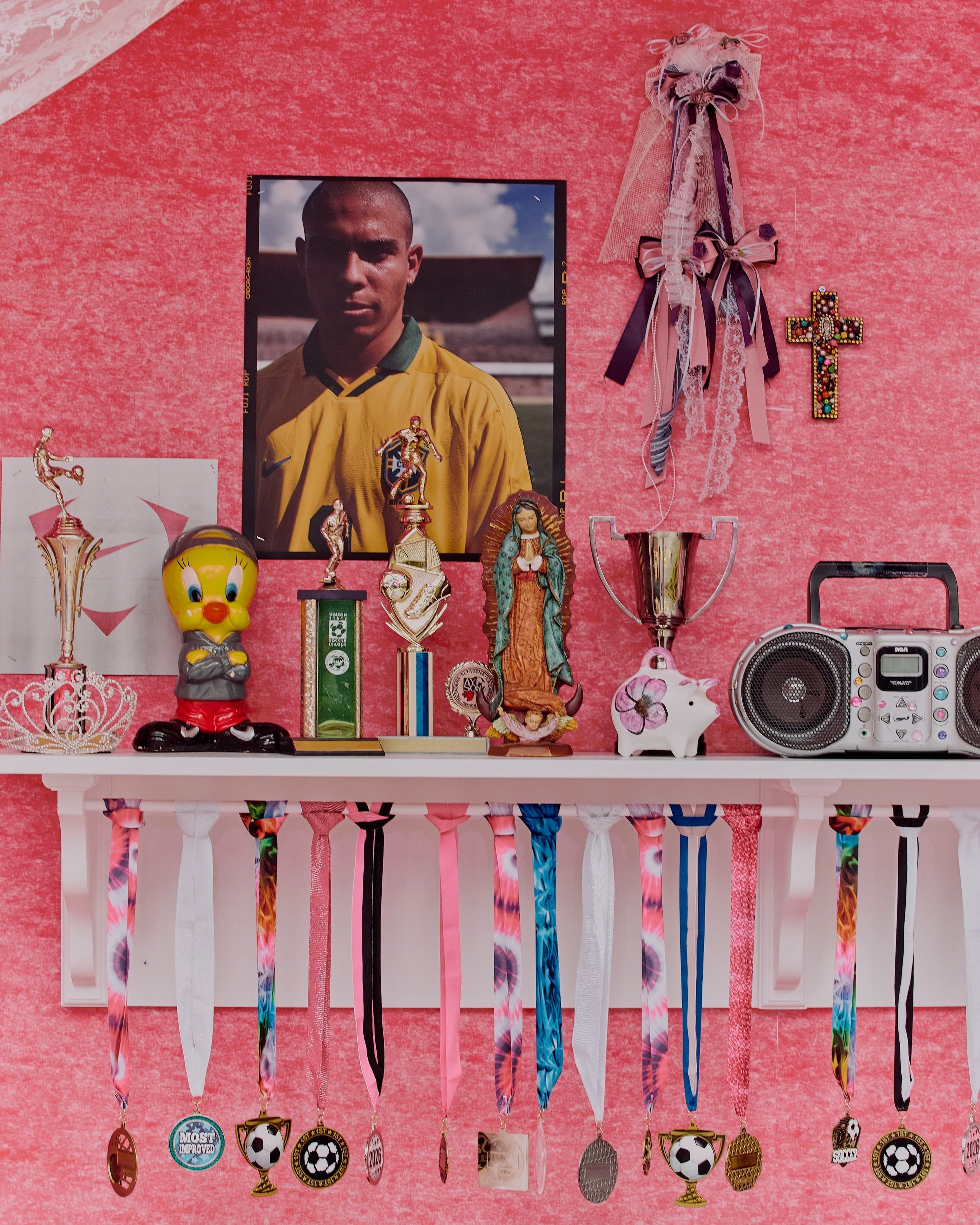 A pink shrine wall with a player portrait, medals and keepsakes
