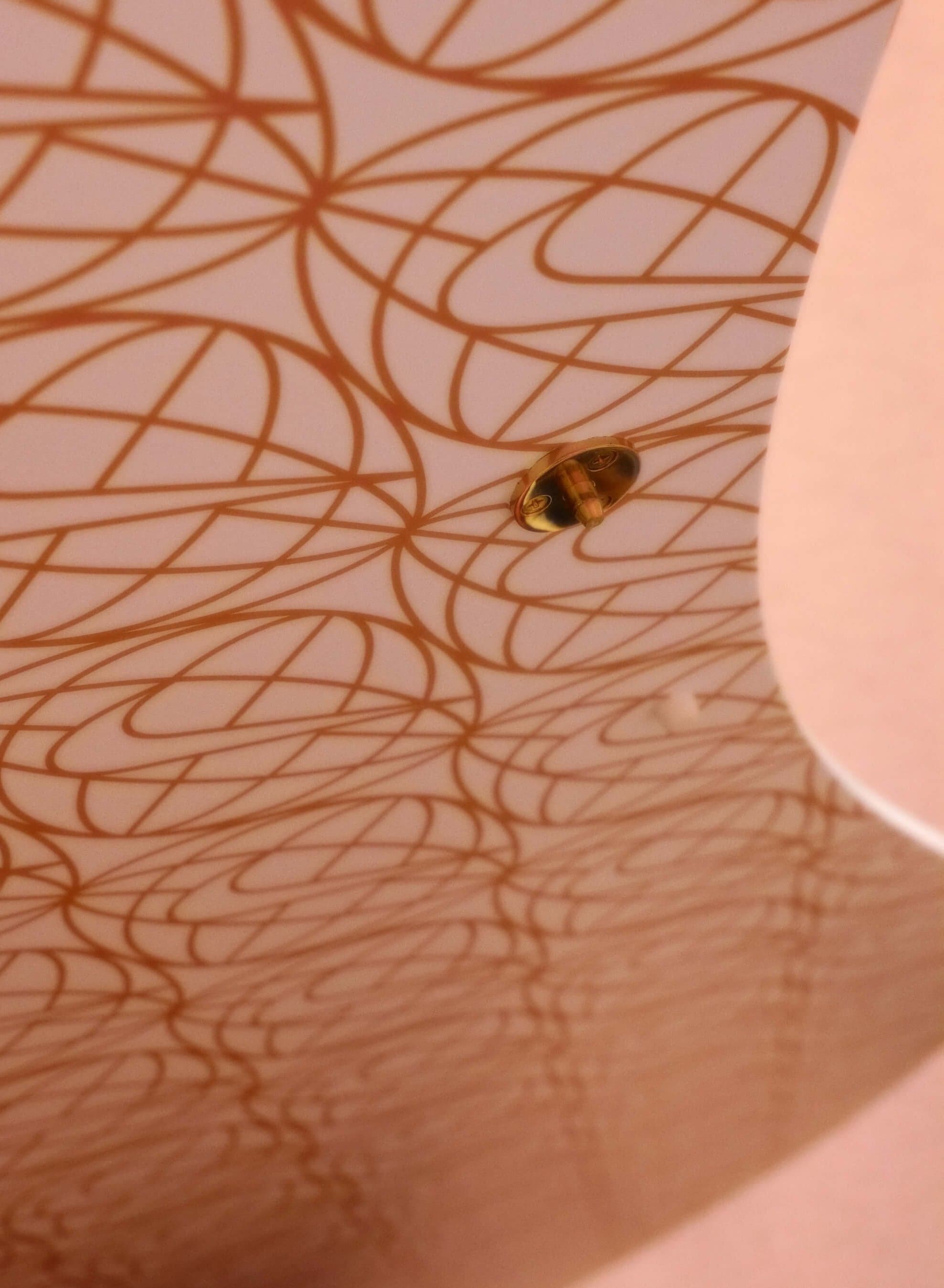 Gold globe-and-swoosh lines printed on a curved pink surface