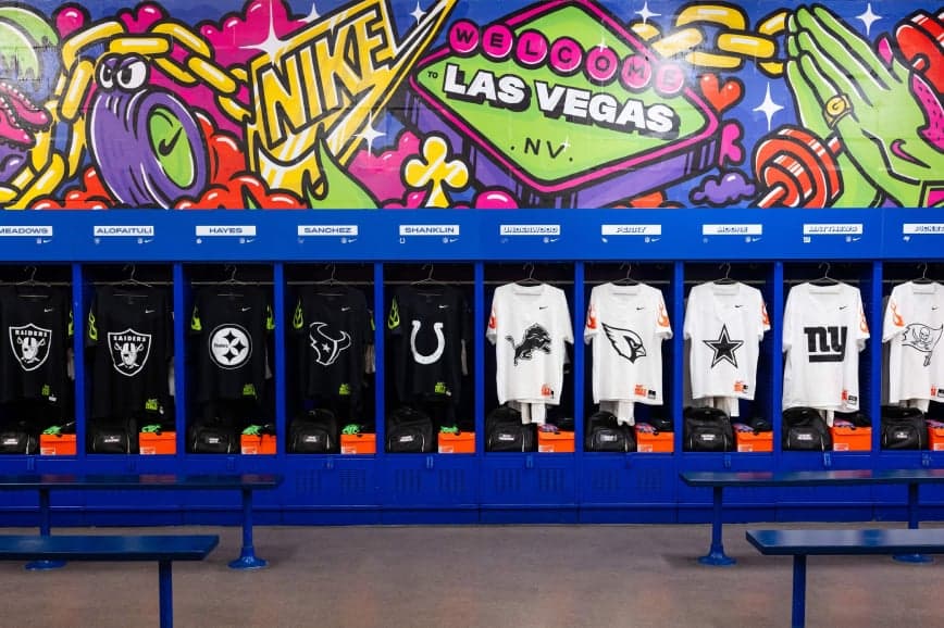 A row of NFL team jerseys hanging in lockers under a graffiti-style Nike mural, with a blue bench below