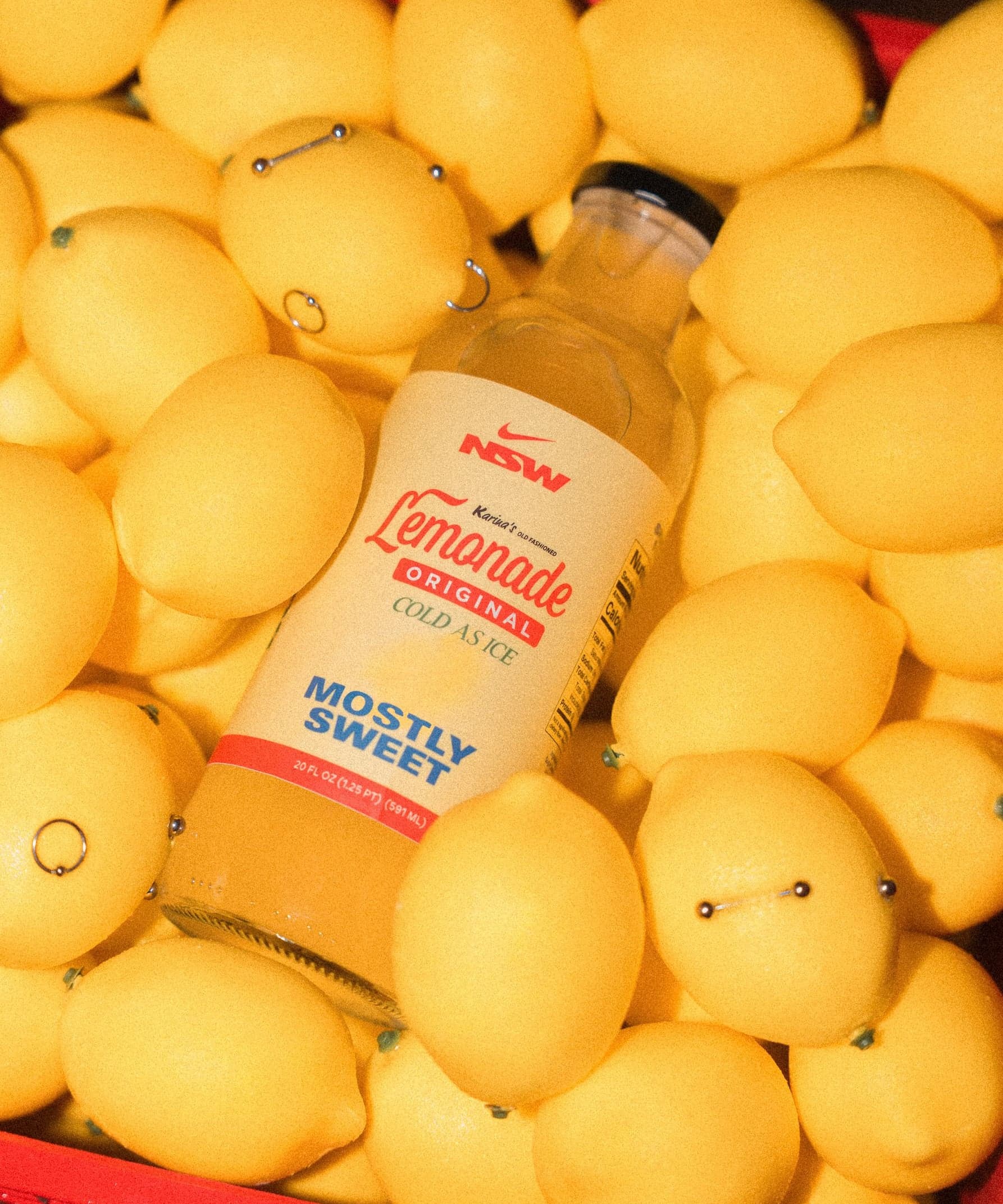 A bottle of Karina’s lemonade nestled among lemons in a red crate