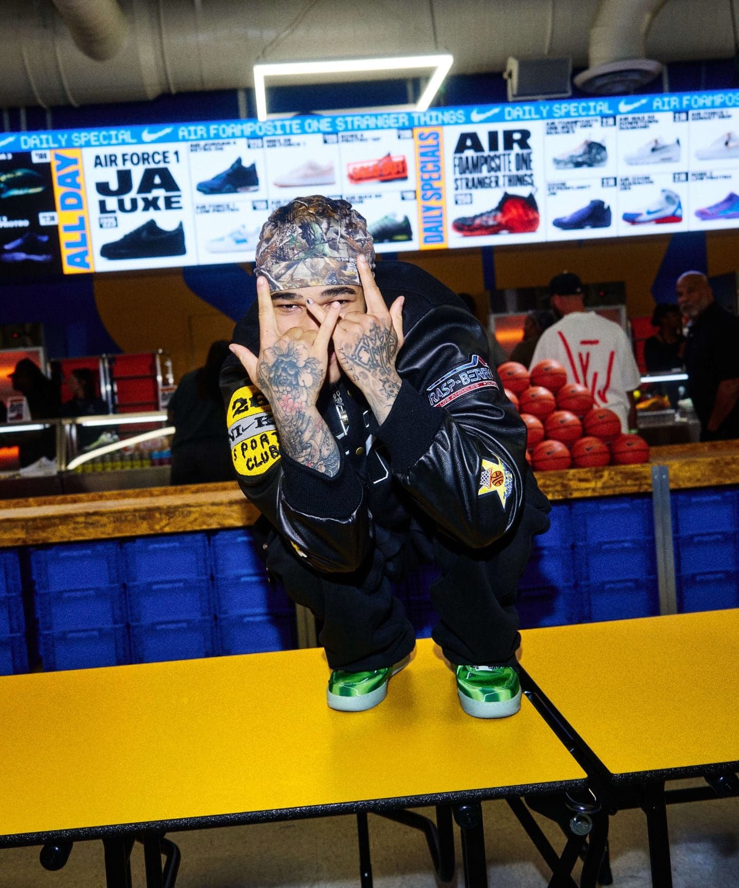 A guest crouching on a yellow cafeteria table beneath the sneaker menu screens