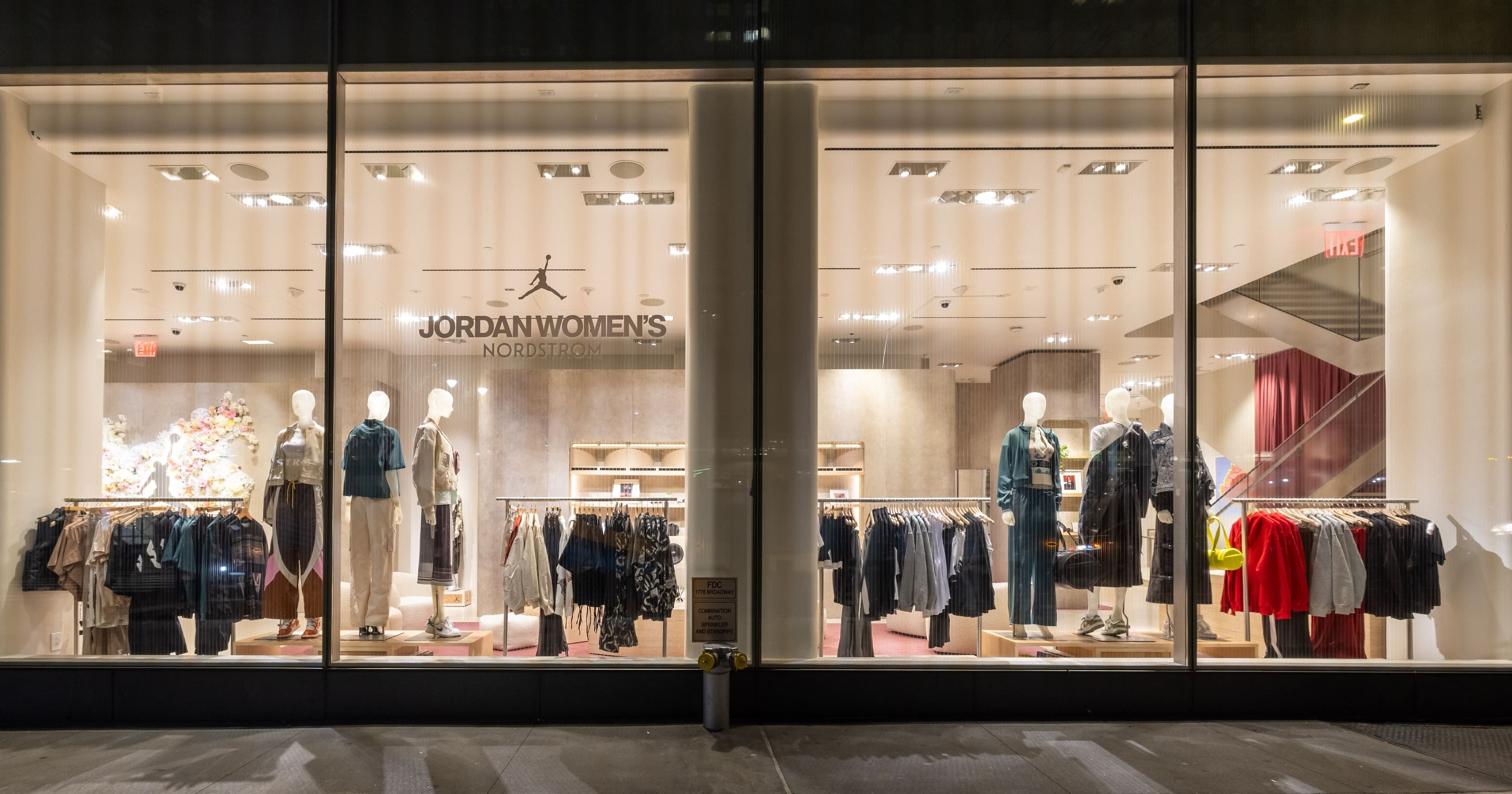 The Jordan Women’s window at night: mannequins in streetwear between rails of clothing
