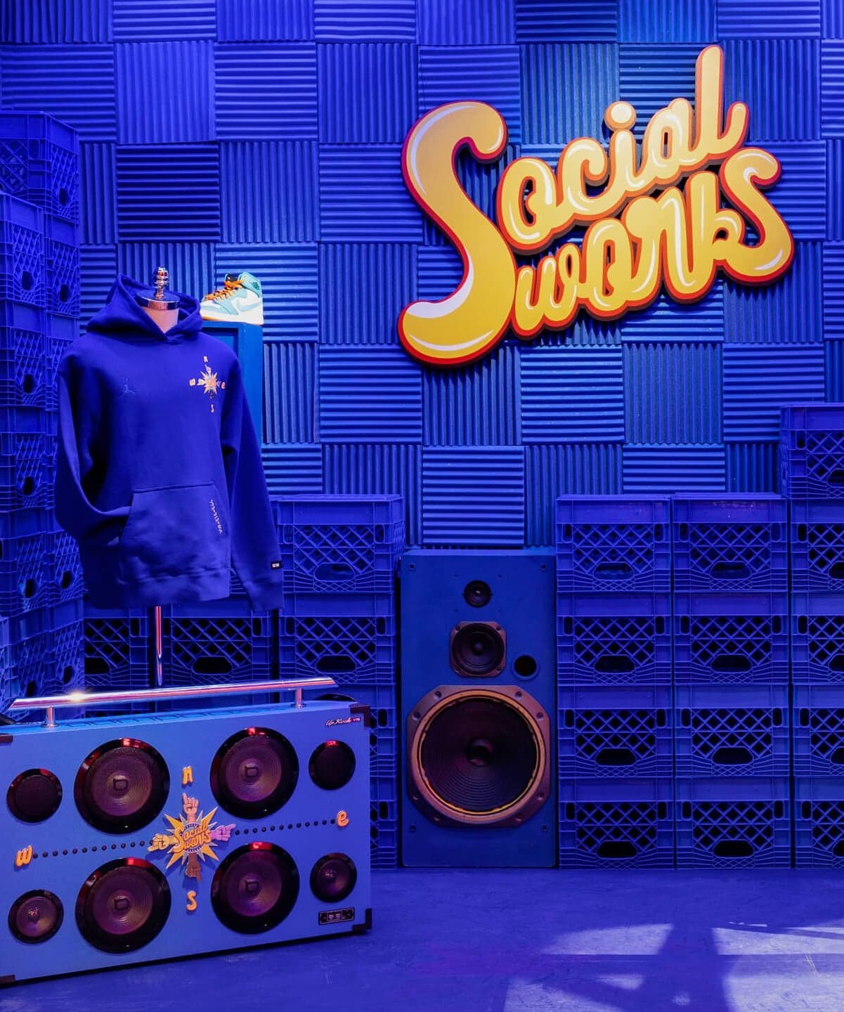 The blue Social Wonks room, with hoodies on mannequins in front of stacked crates and a boombox