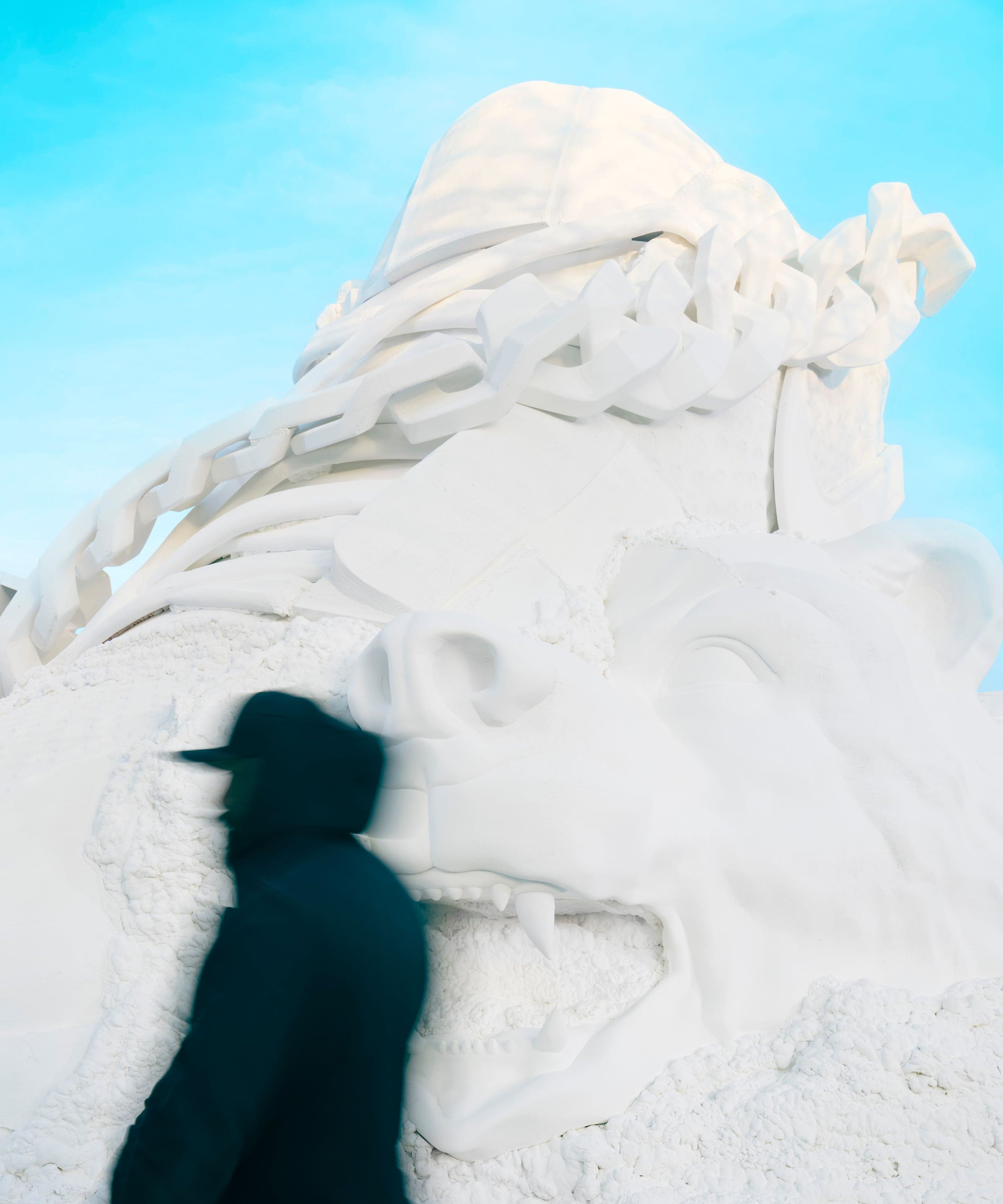 A visitor’s blurred silhouette against the carved snow sculpture