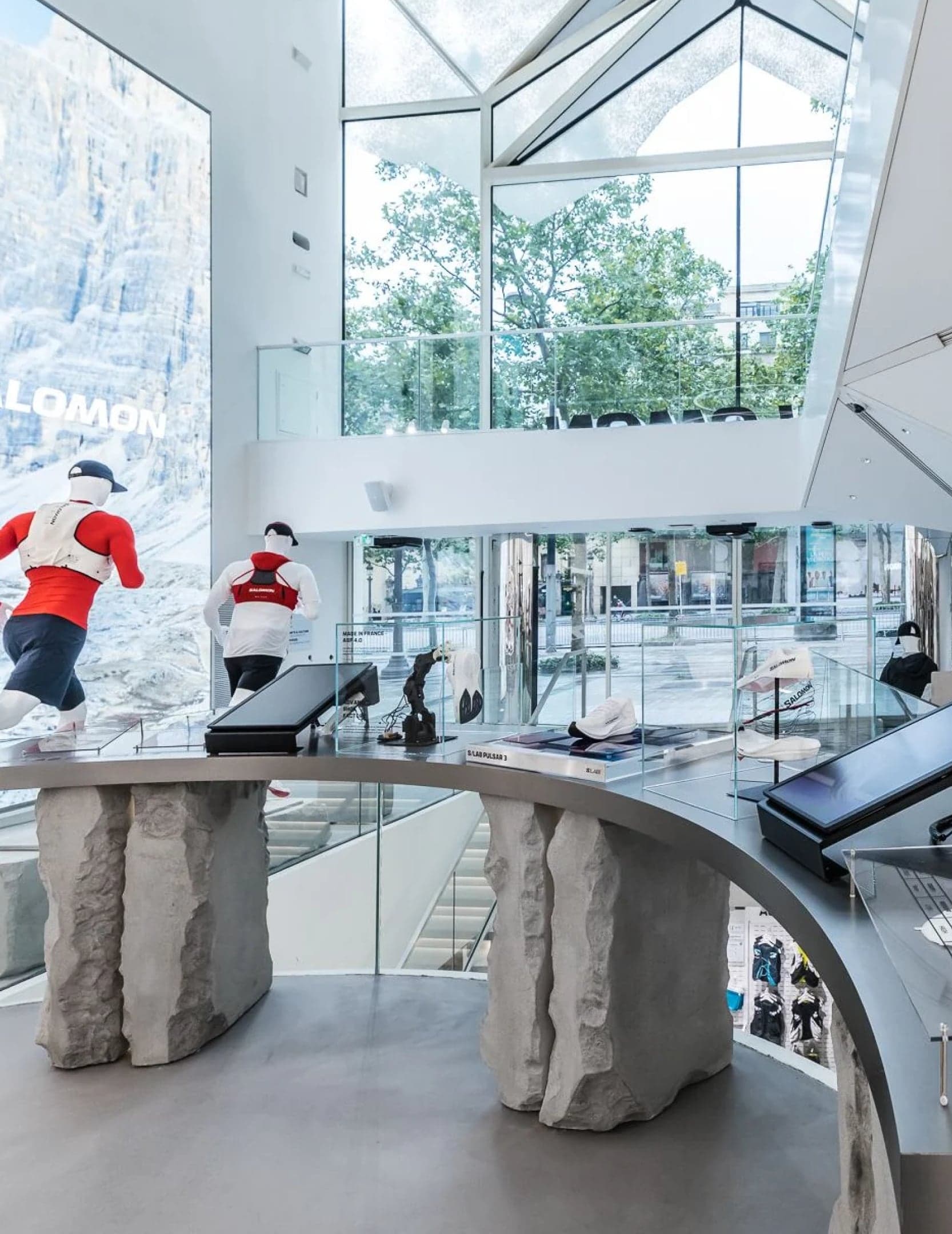 Display tables on rough stone plinths in front of a mountain screen and tall windows