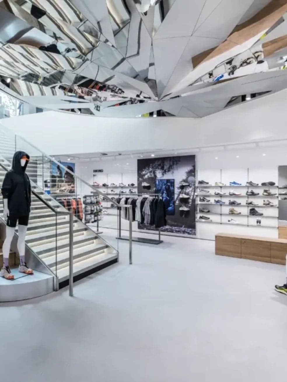 A wall of shoes beside the staircase under a mirrored ceiling