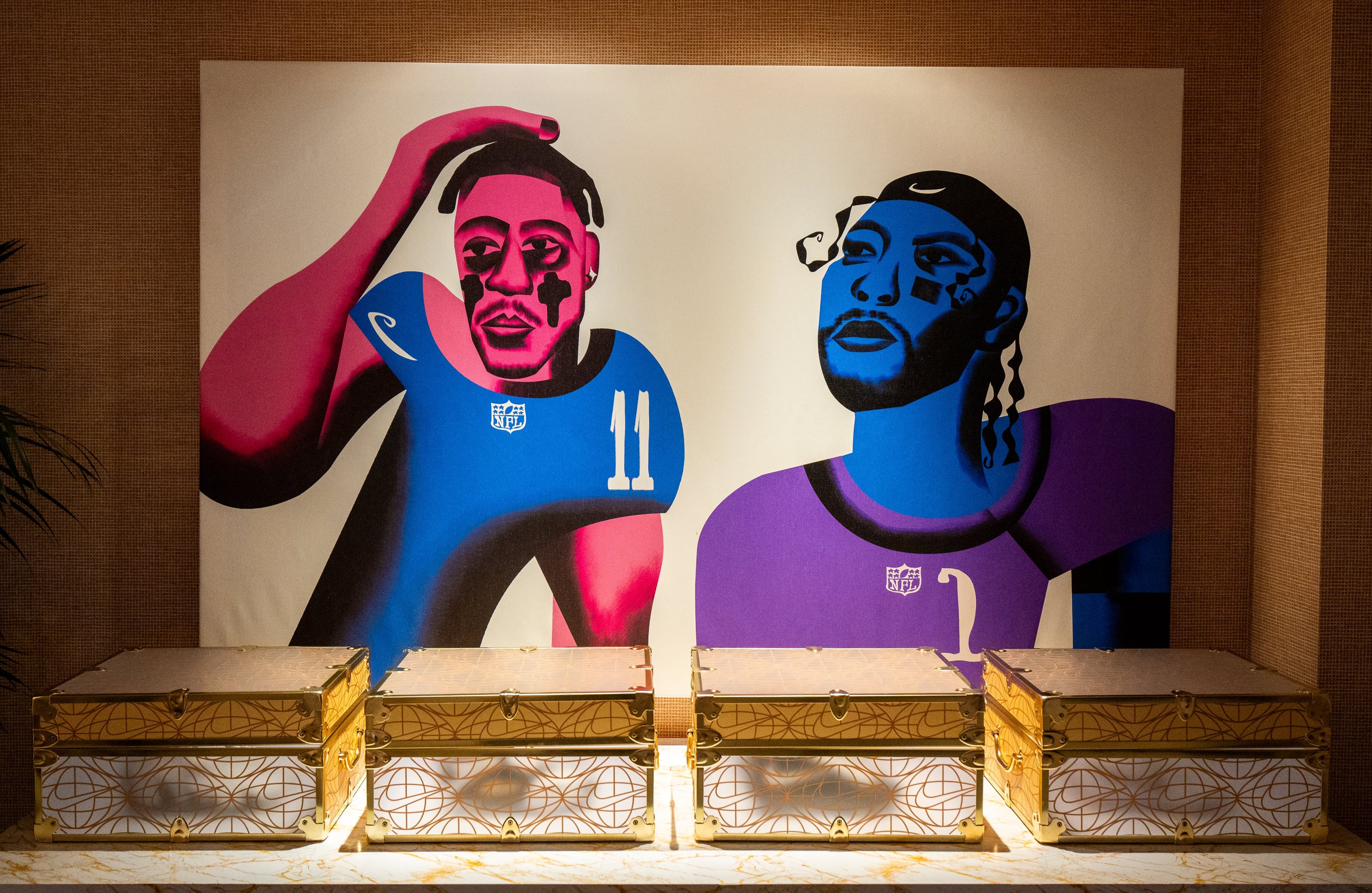 Two large illustrated portraits of NFL players hung above gold trunks