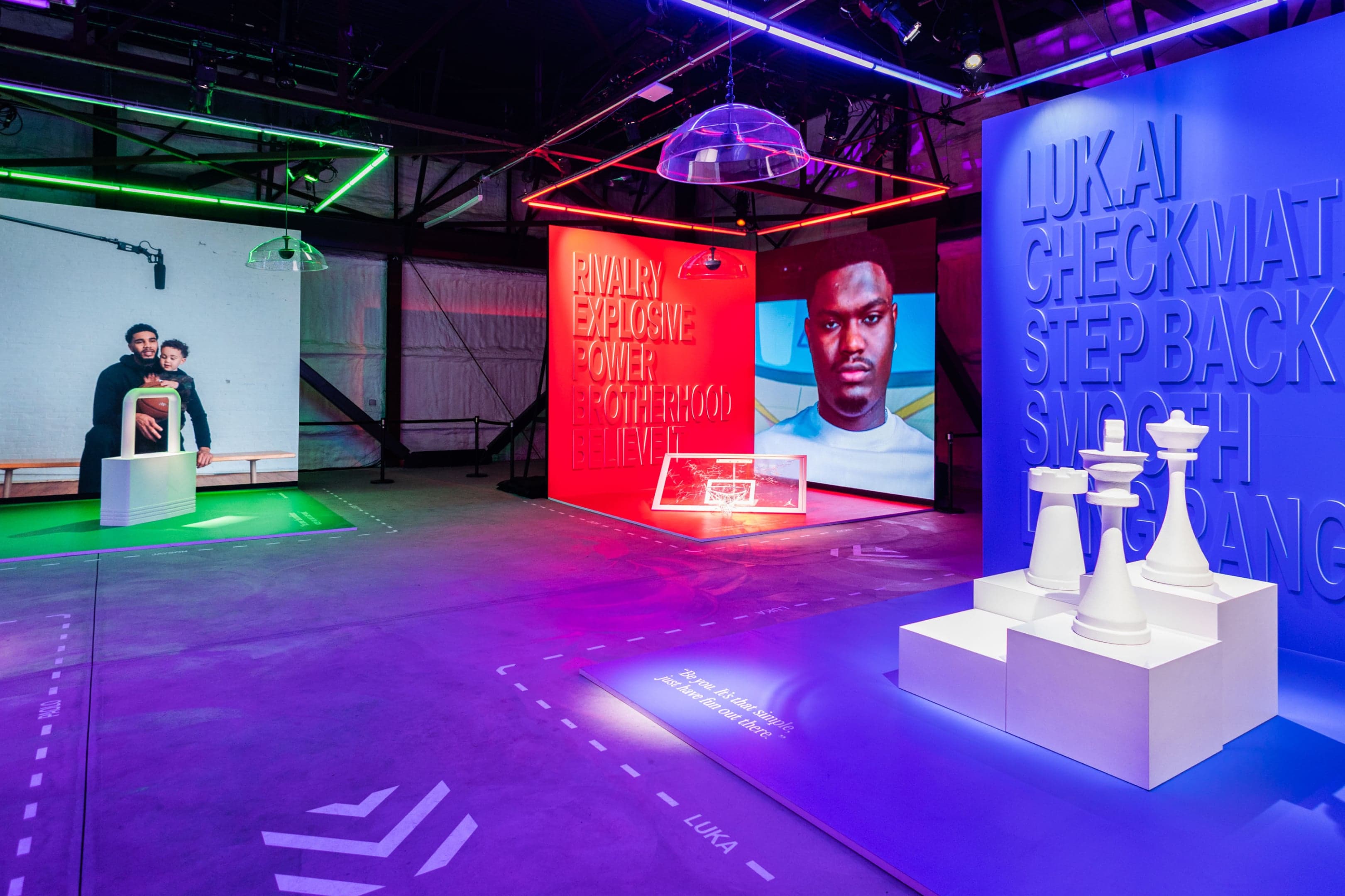 Neon-lit player rooms: white chess pieces on plinths before a blue “Luka: Checkmate, Step Back” wall, beside a red “Rivalry” room with a hoop and portrait