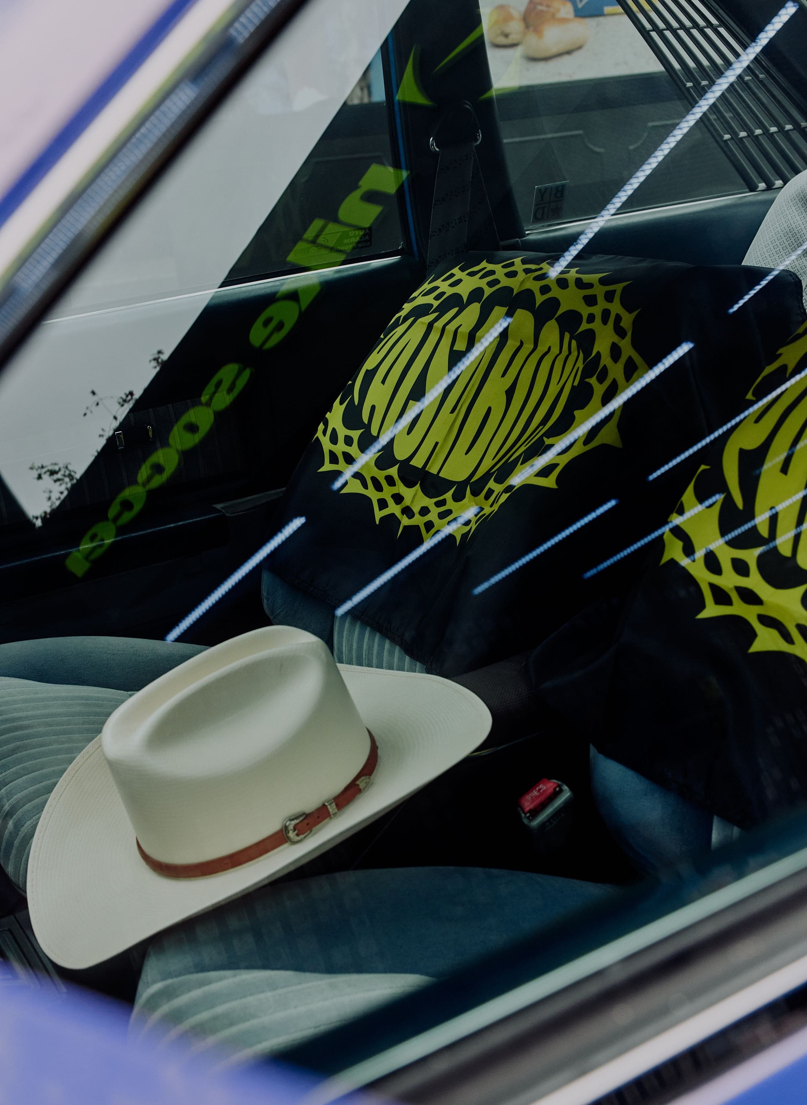 A cowboy hat on a car dashboard with the Paisa Boys logo
