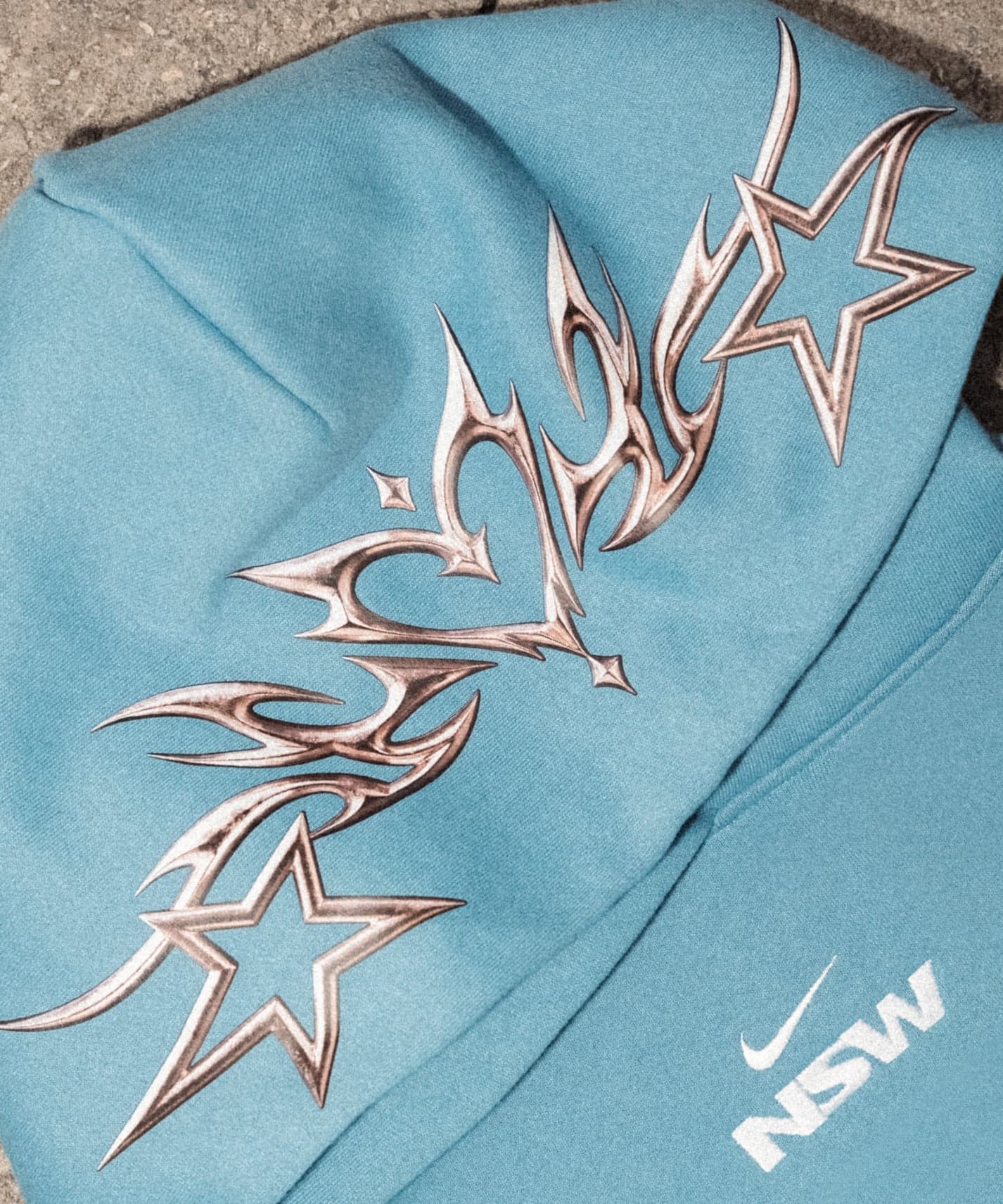 Close-up of the hoodie’s chrome flame-and-star graphic and NSW logo