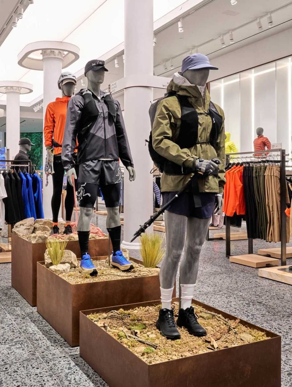 Mannequins in outdoor jackets on wooden plinths across the store floor