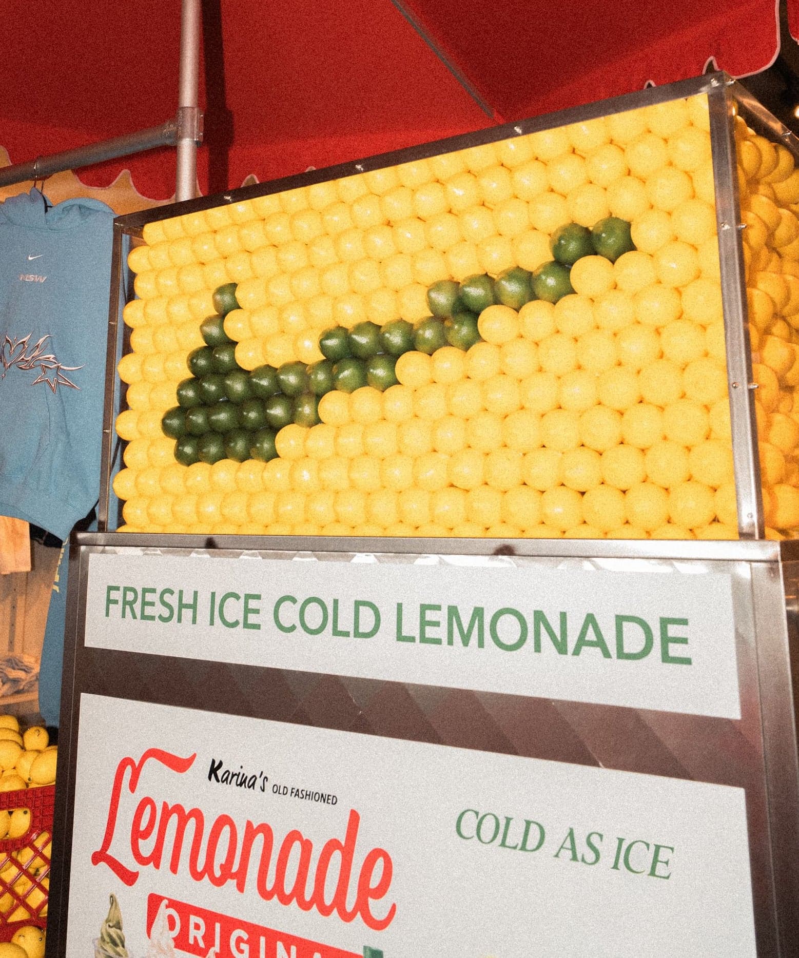 A wall of lemons forming a Nike swoosh above “Fresh Ice Cold Lemonade” signs