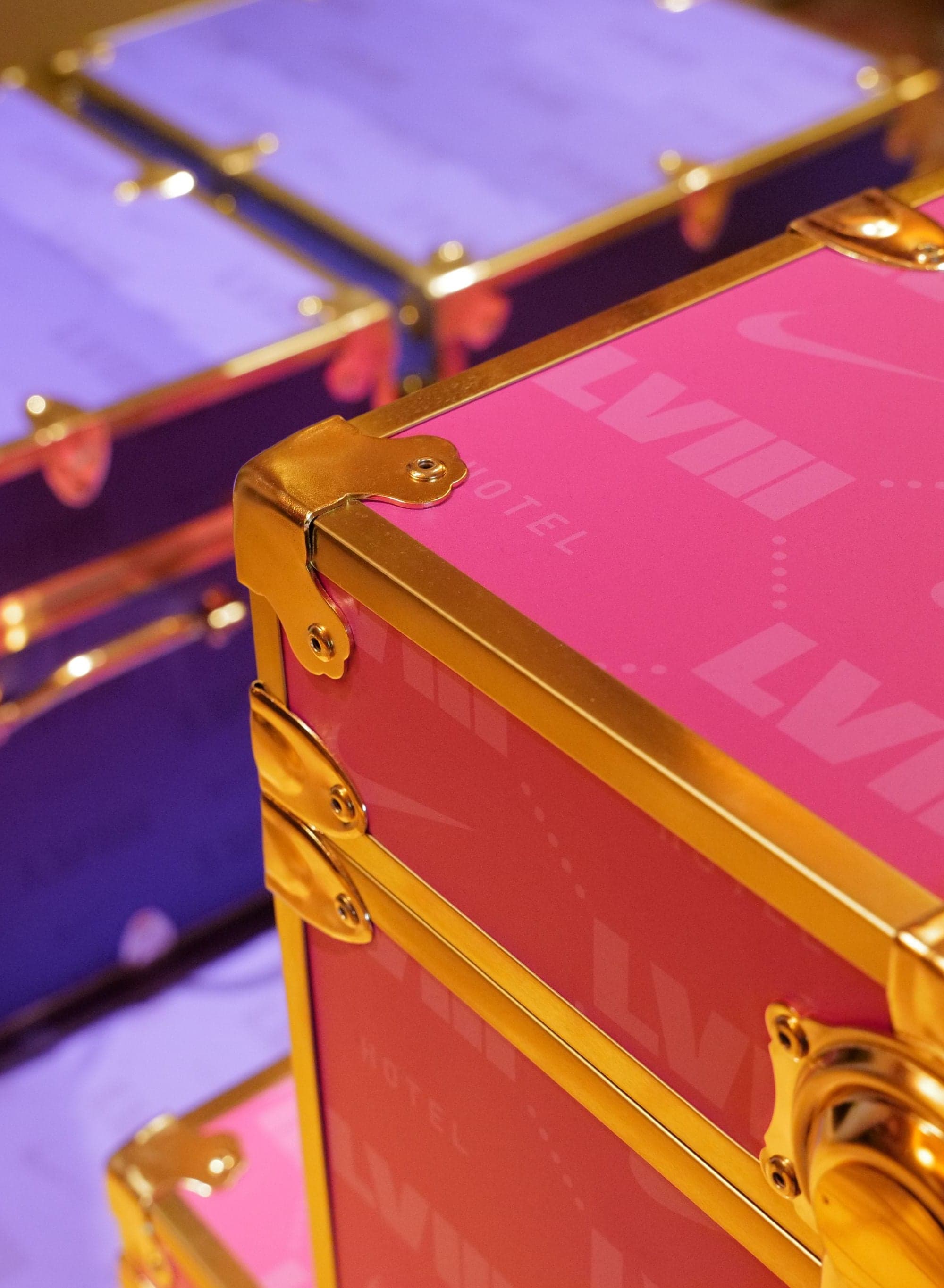 Pink and purple trunks with gold corners, printed with LVIII and swooshes