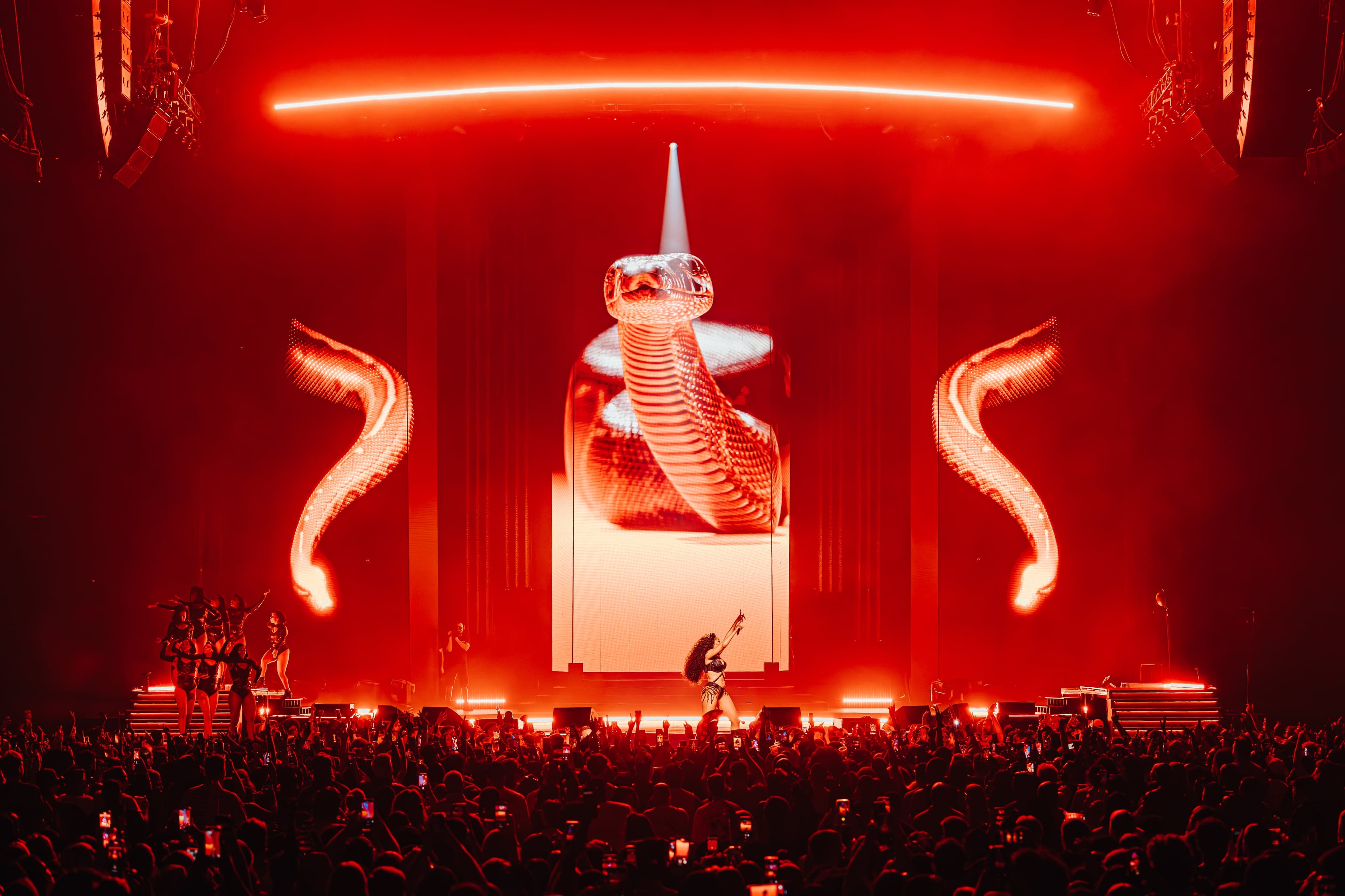 A giant snake coiled on the centre screen, flanked by glowing horns, with the stage bathed in red