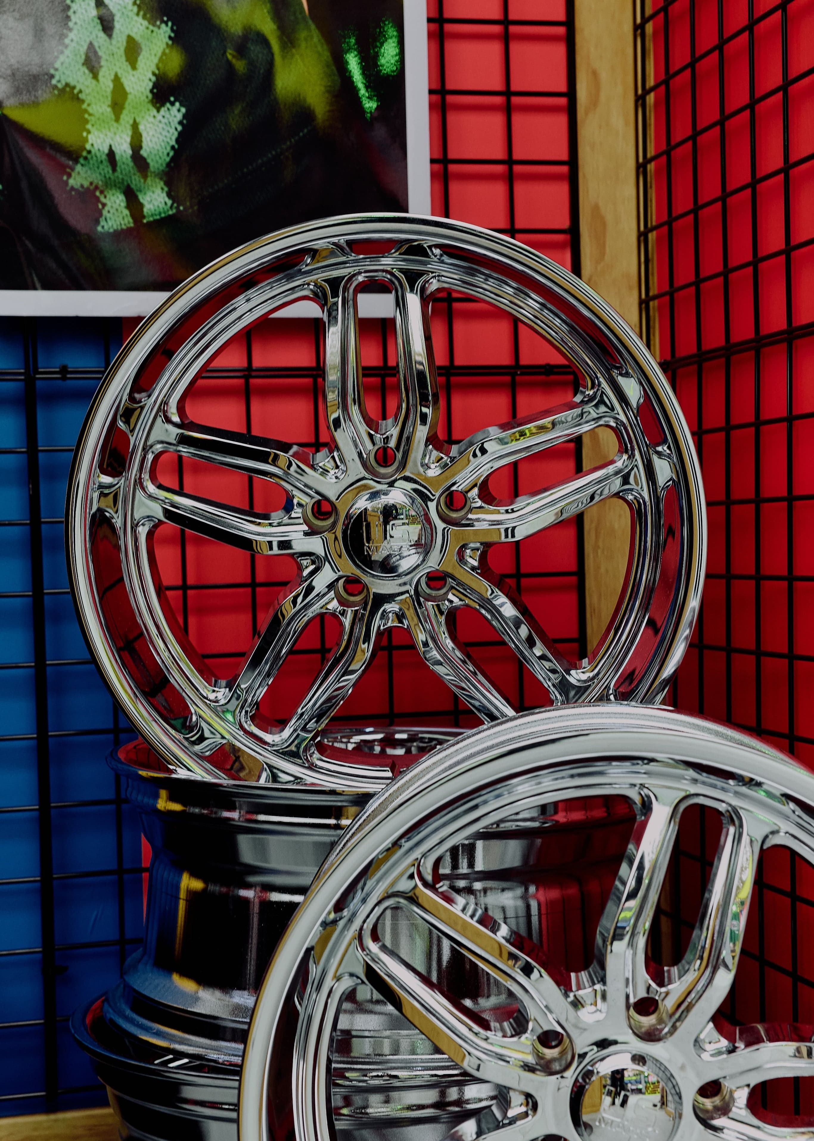 Chrome car rims on a red grid wall