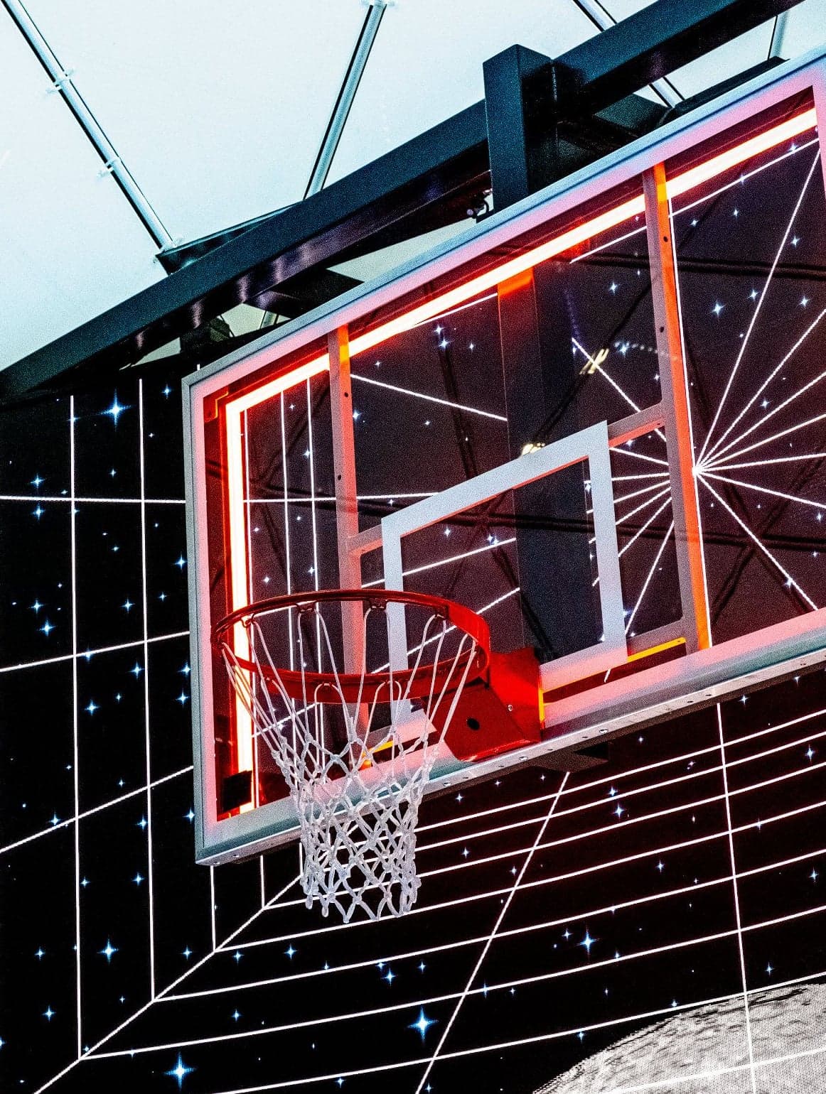 The LED-lit backboard and hoop against the starry grid of the curved screen