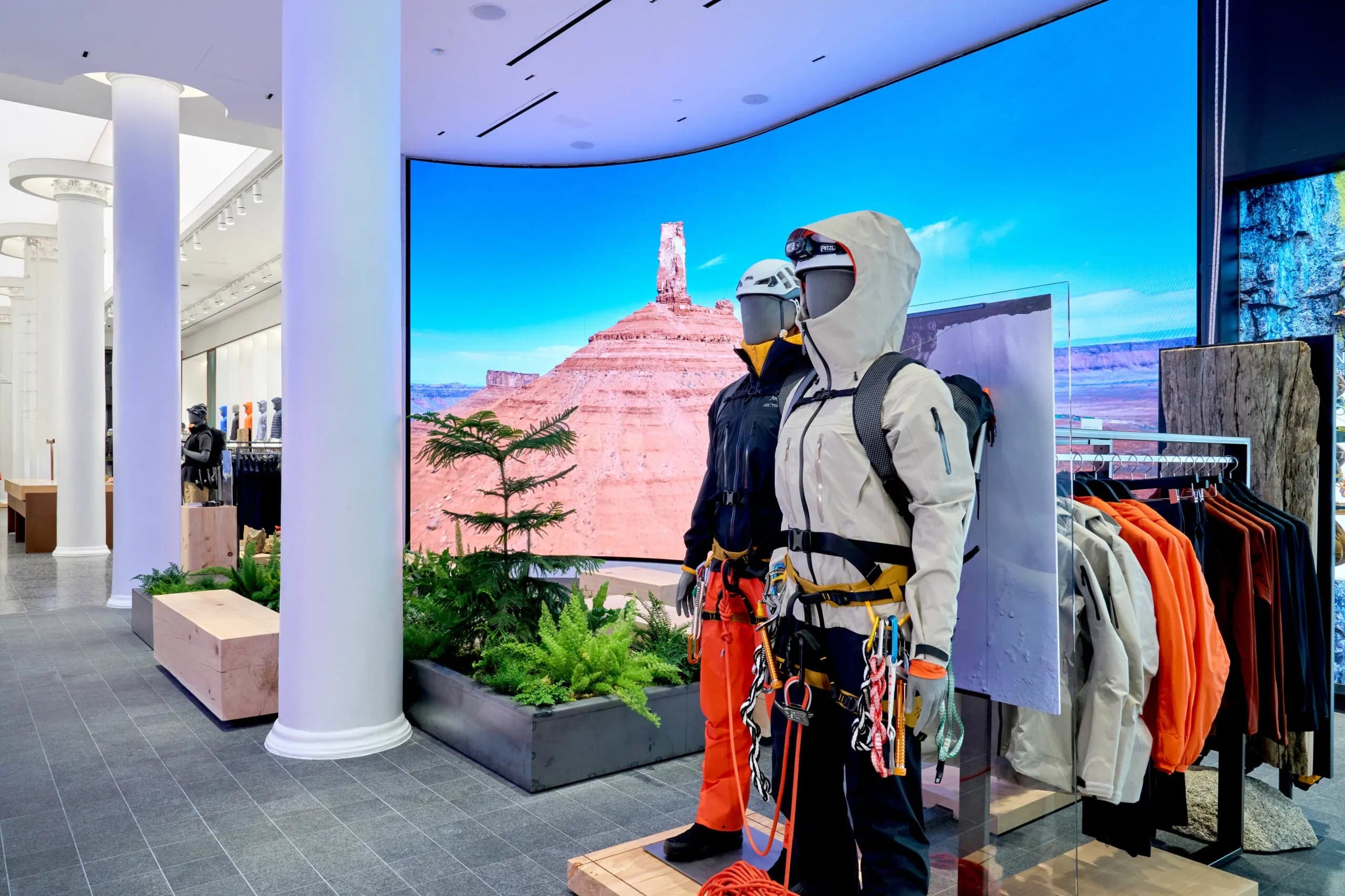 Mannequins in climbing gear in front of a curved LED wall showing desert cliffs