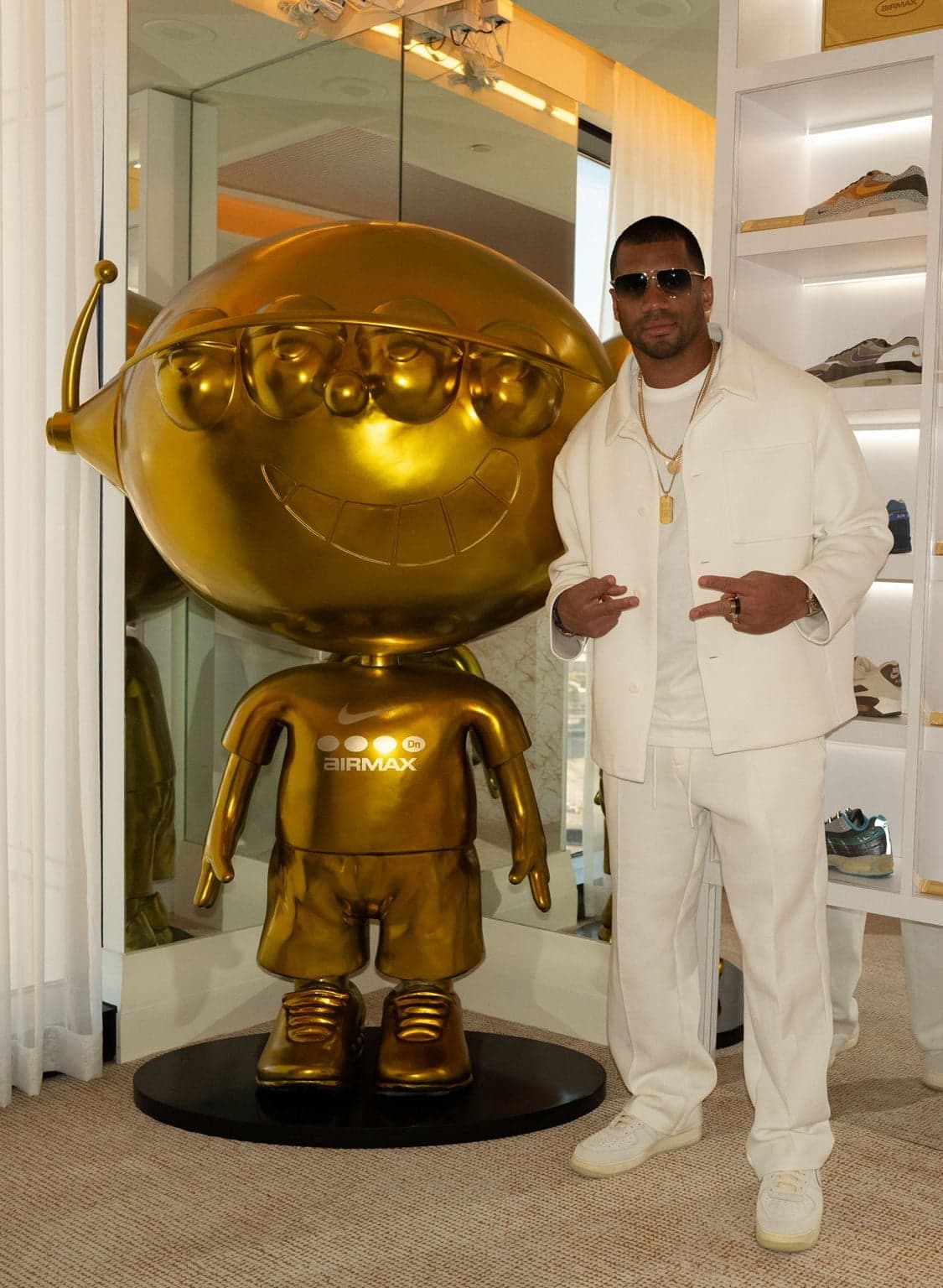 A guest in white posing beside the life-size gold figure in the Air Max closet