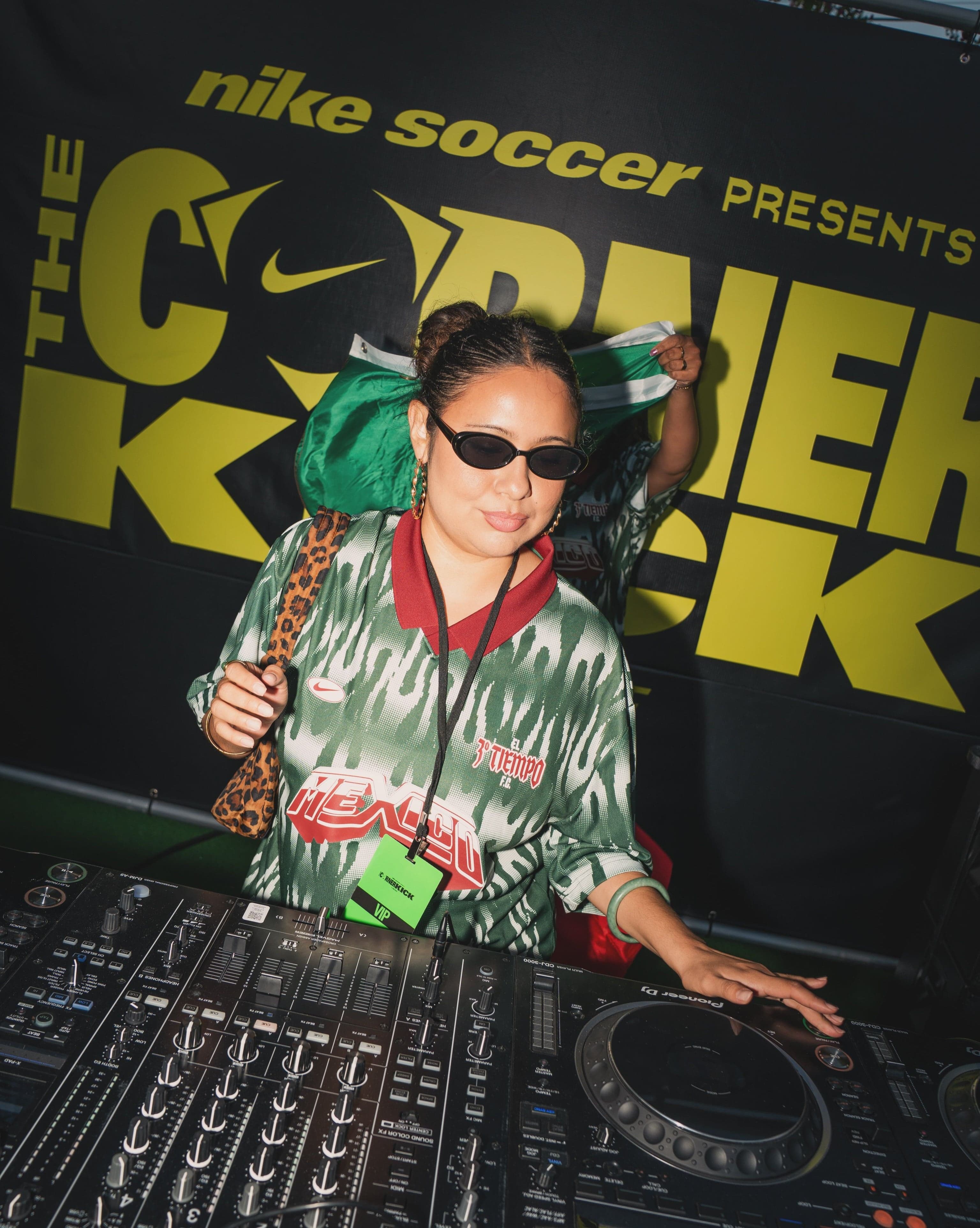 A DJ playing in front of a Nike Soccer presents Corner Kick backdrop
