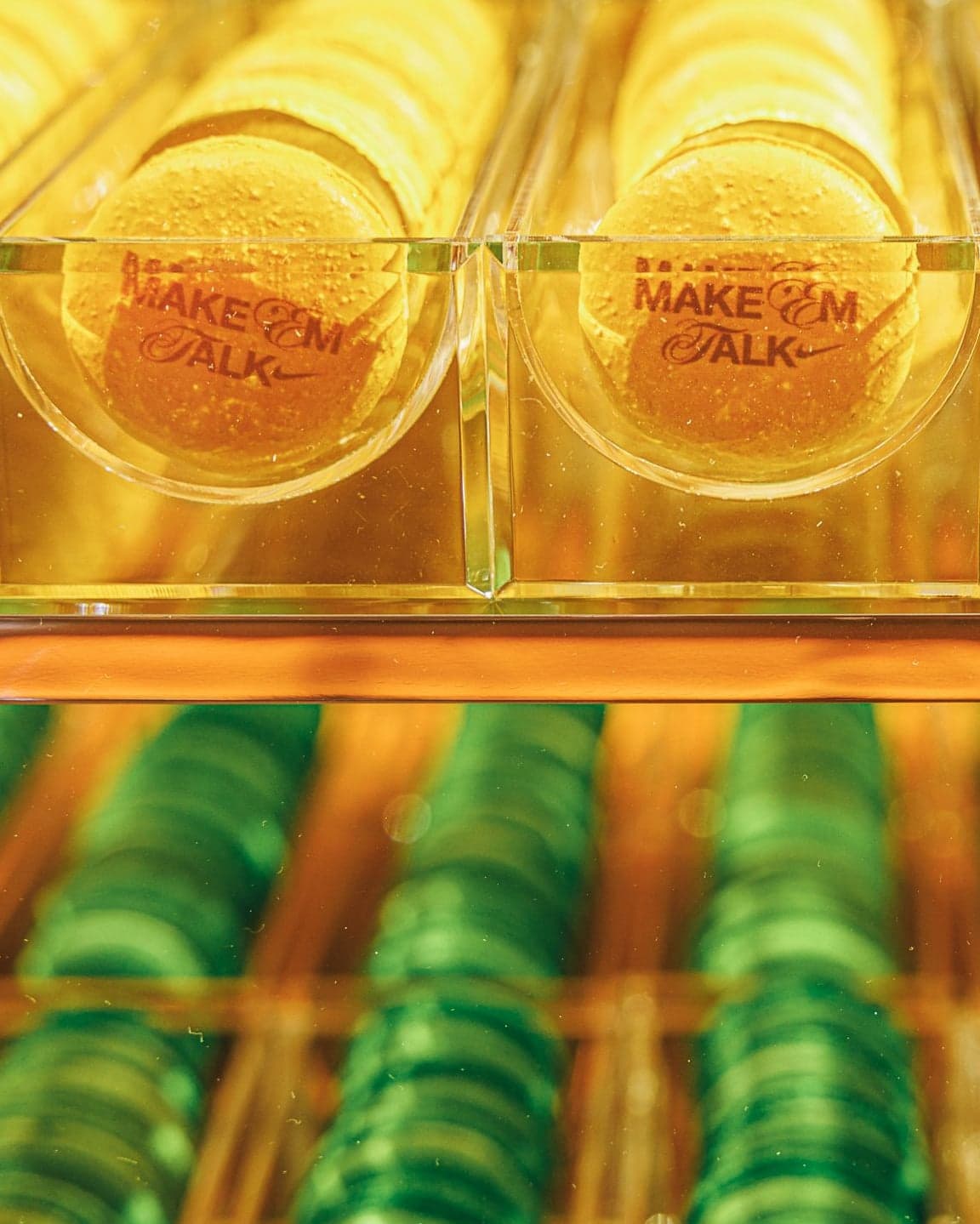 Make ’Em Talk iced tea glasses above rows of green macarons