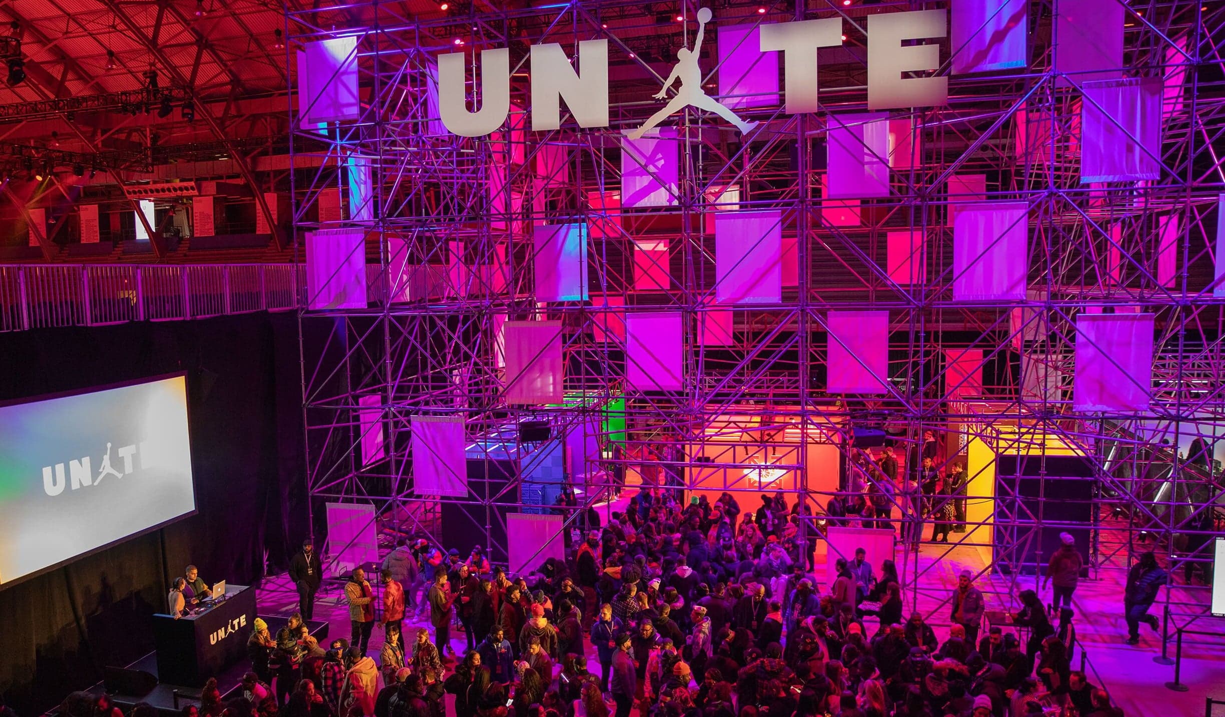 A crowd in front of the UNITE stage, a wall of purple and pink light boxes under the UNITE sign