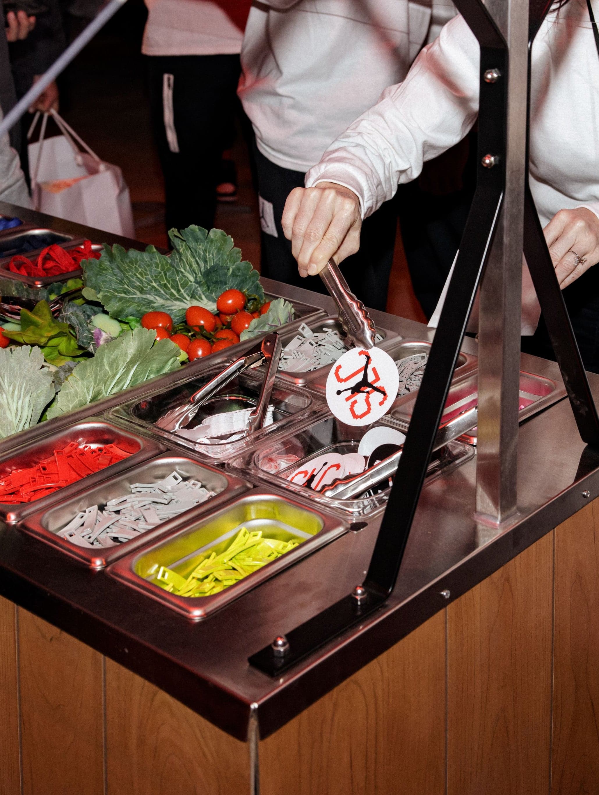 Staff picking toppings at the customization bar beside a Jordan bag