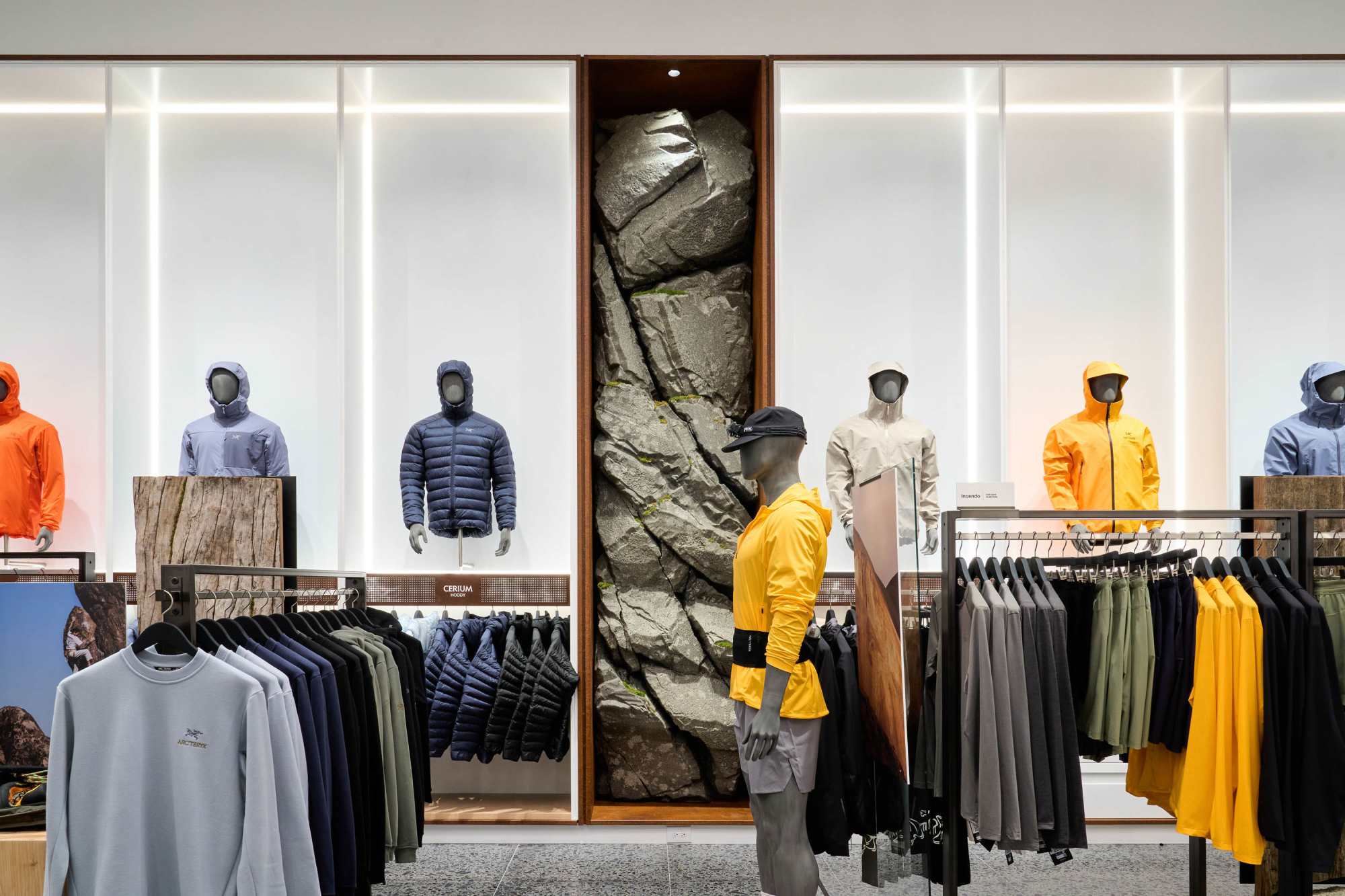 Jackets on rails and mannequins either side of a tall rock-face feature wall