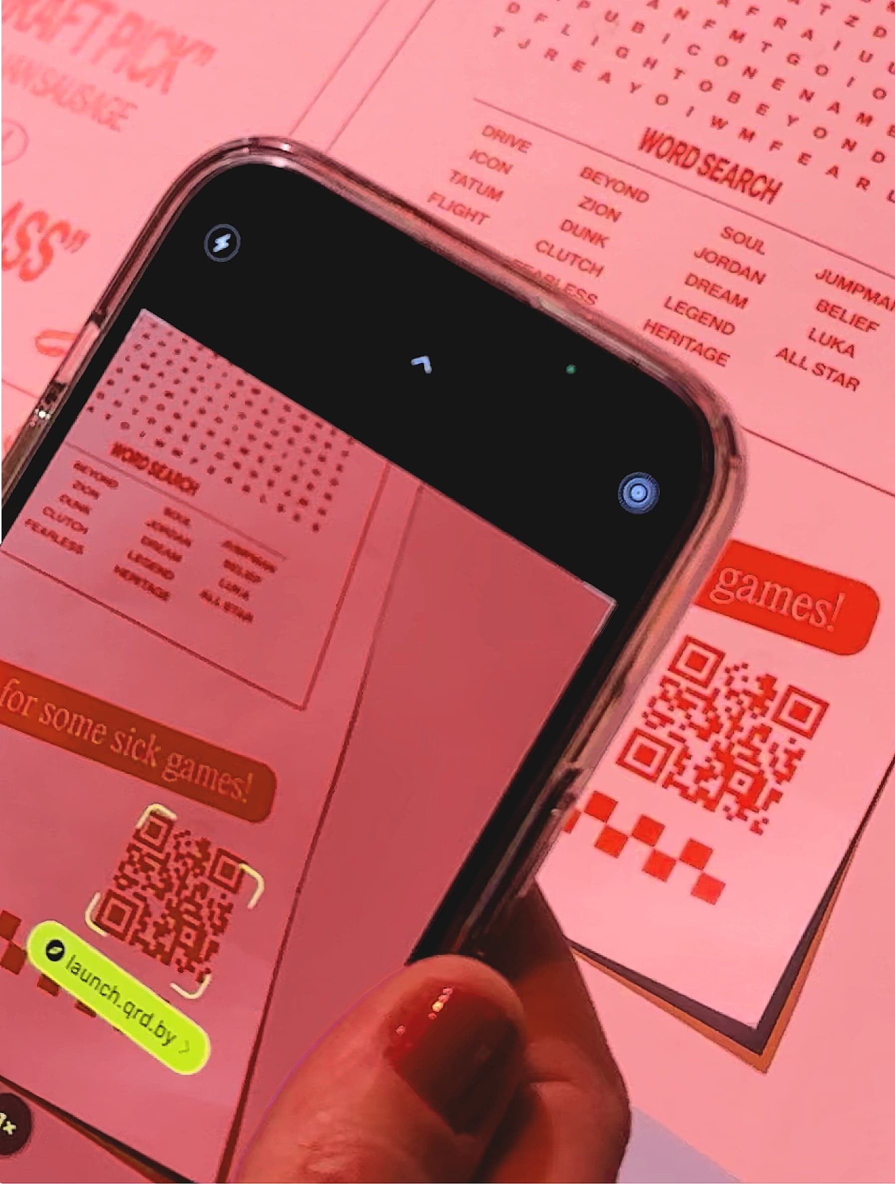 A hand holding a phone over the pink Parlor 23 menu, its QR code on screen