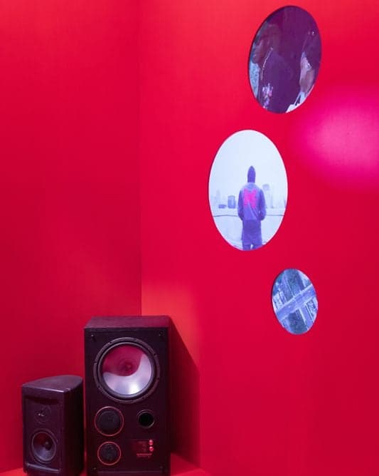 A red room with a speaker and round windows showing a figure on a court