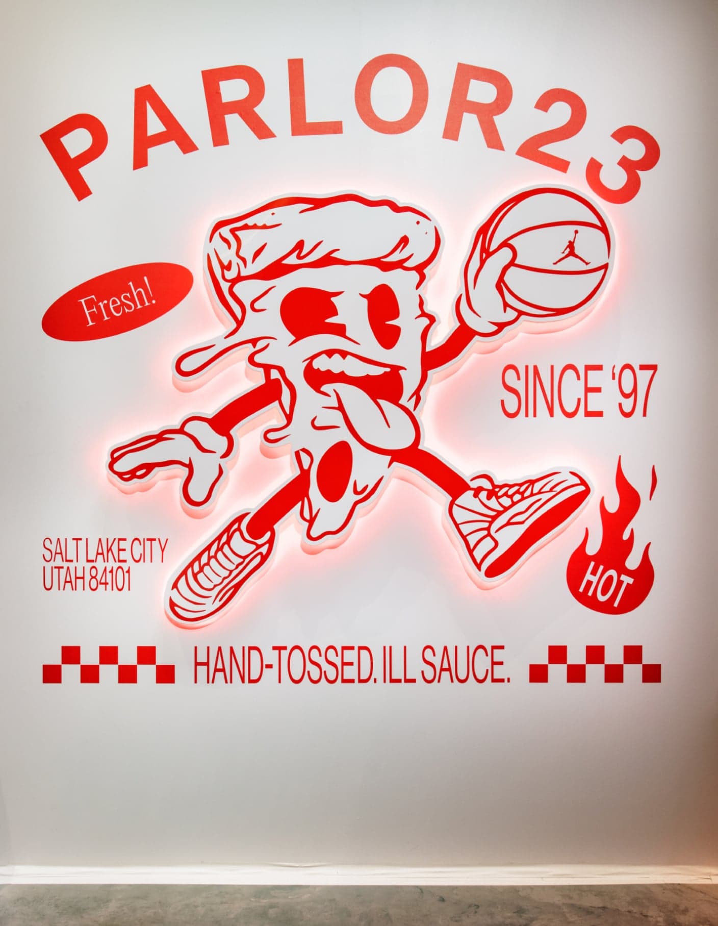 The neon Parlor 23 sign: a pizza slice mascot dribbling, with “Since ’97” and “Hand-tossed. Ill sauce.”