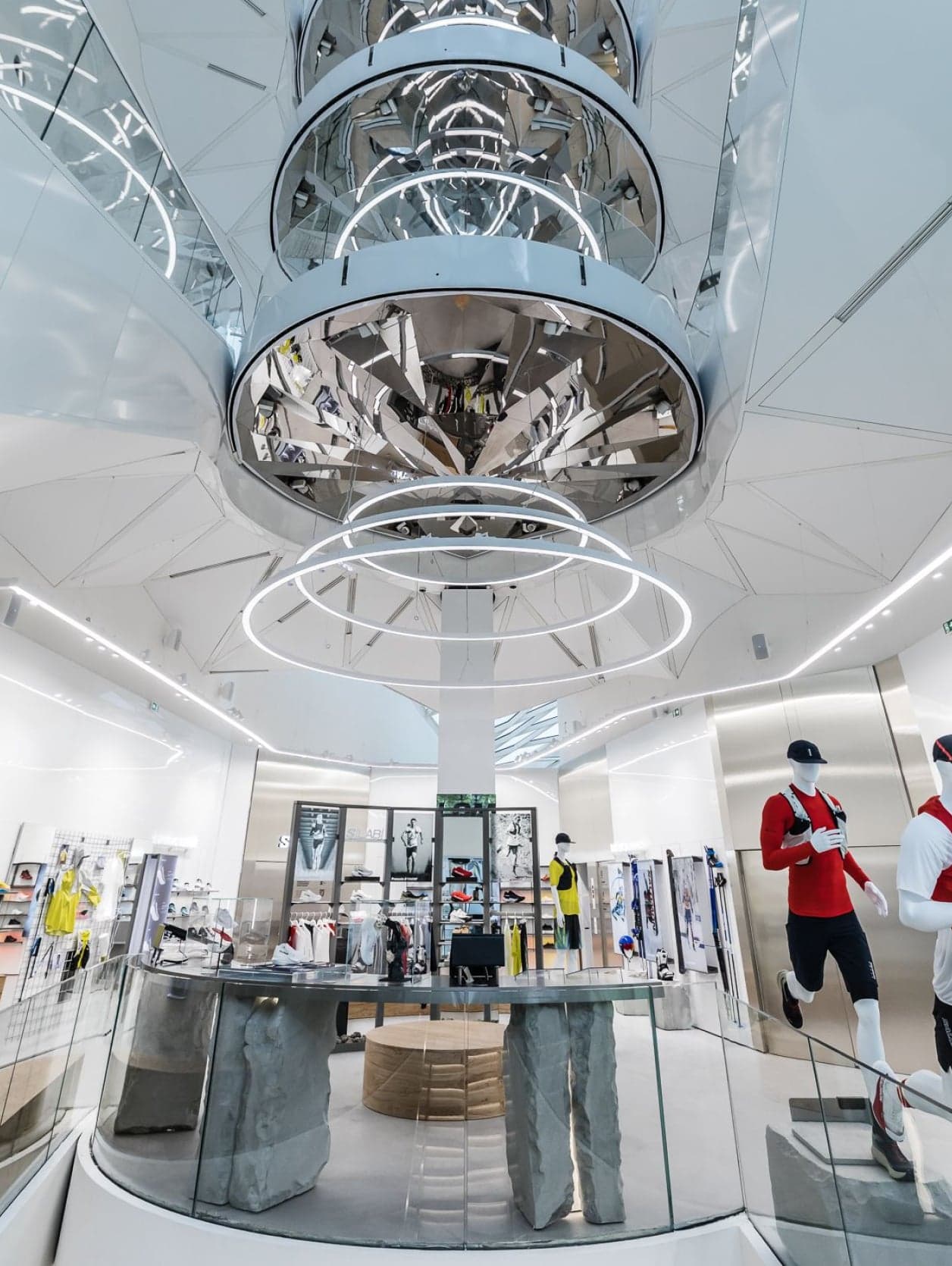 A mirrored, ringed chandelier hanging above the atrium and its displays