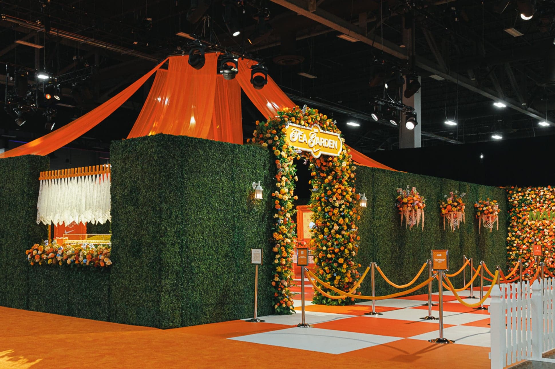 The orange and green Tea Garden entrance, with a flower arch and a draped canopy over a checkered floor